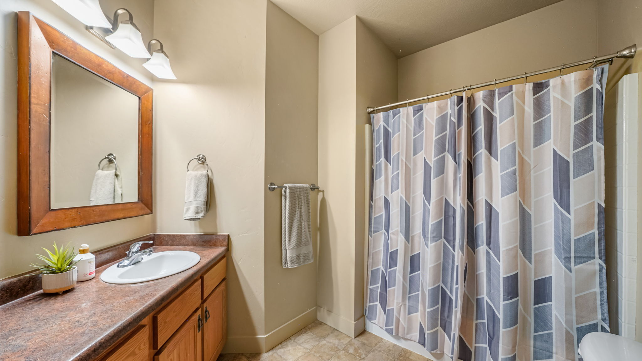 Bathroom featuring a wood-framed vanity mirror, single basin sink, and a shower with a privacy curtain