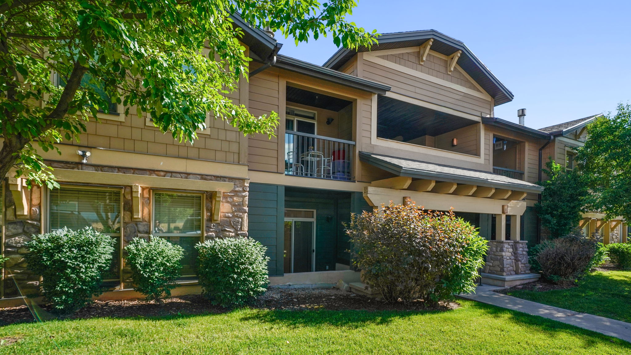 Multi-level exterior with shingle and horizontal siding, stone accents, and a covered balcony