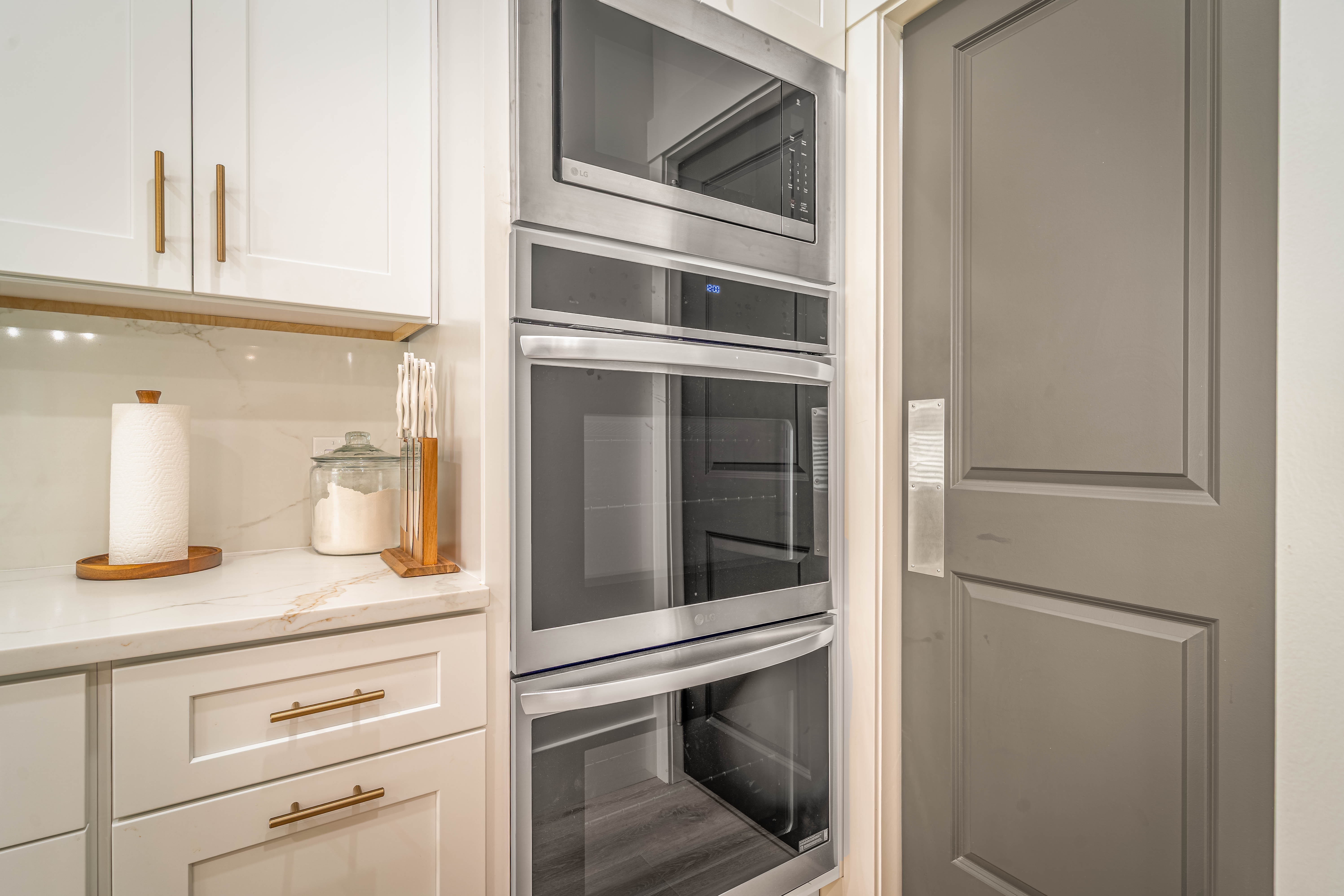 Built-in stainless steel double ovens and microwave complement the light cabinetry and integrated under-cabinet lighting