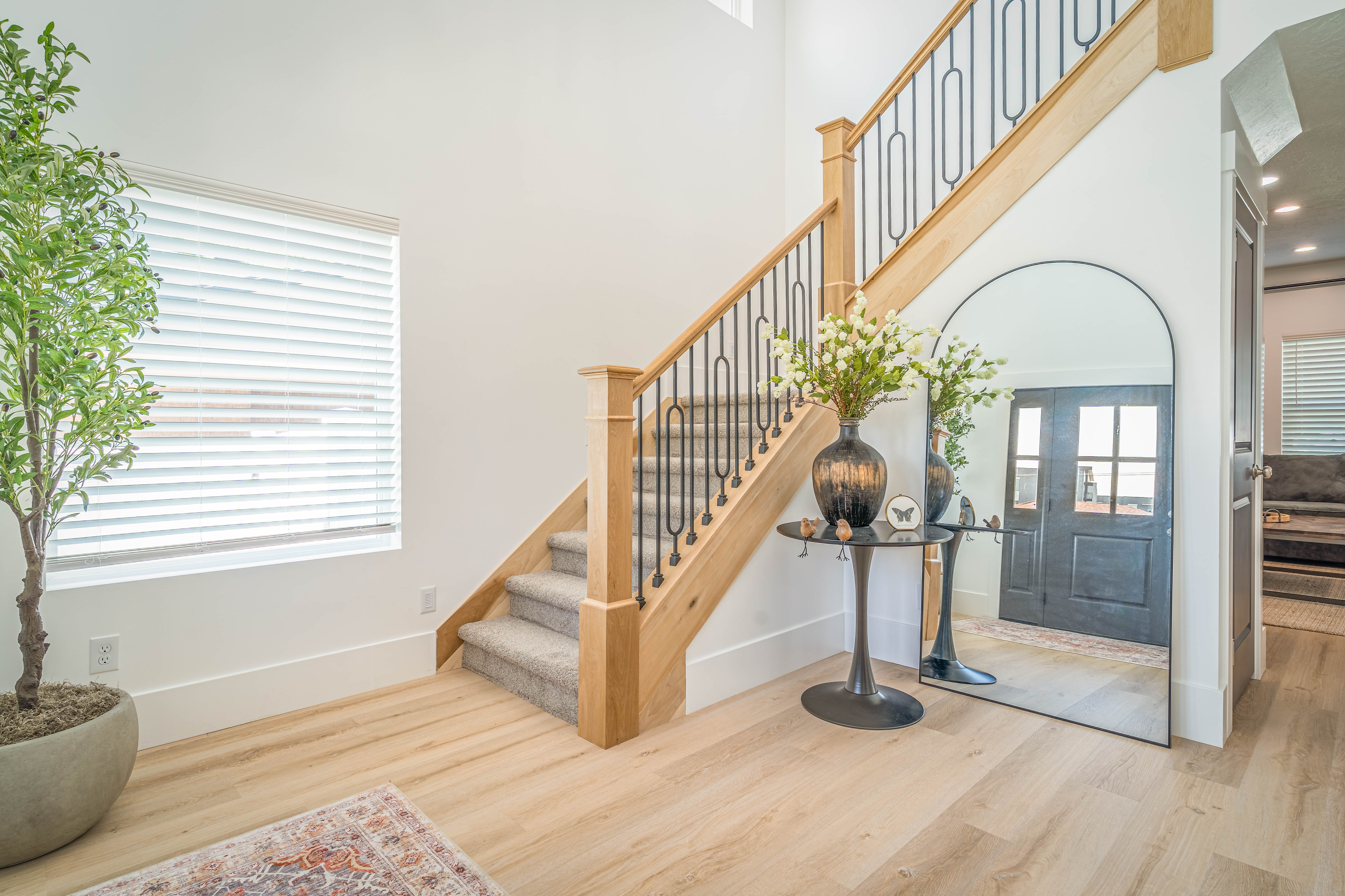 Entryway featuring a grand staircase with light wood newel posts and black wrought iron balusters