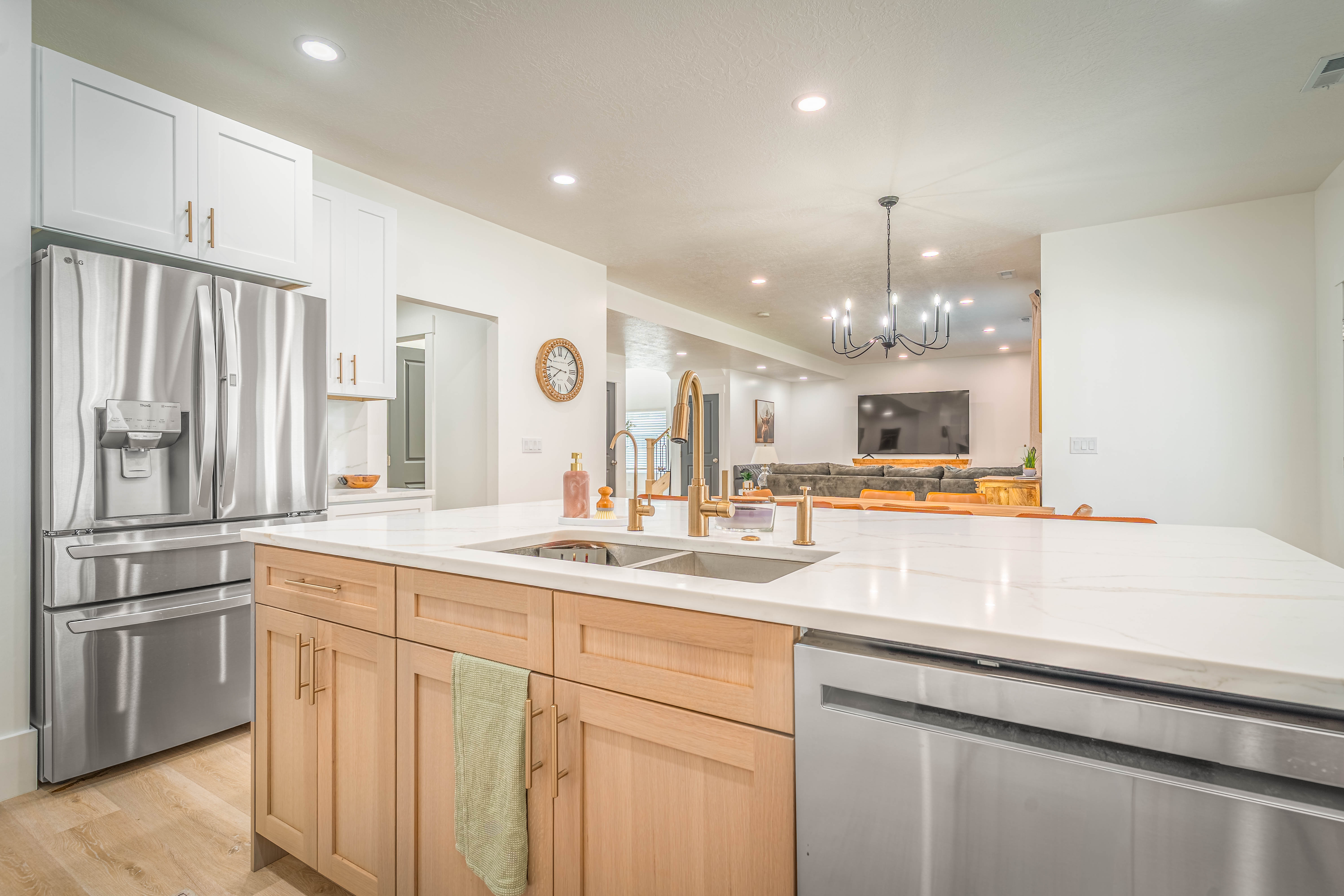 Kitchen island featuring a double basin sink with brass-finish faucet, light wood-finish cabinetry, and a light-toned countertop