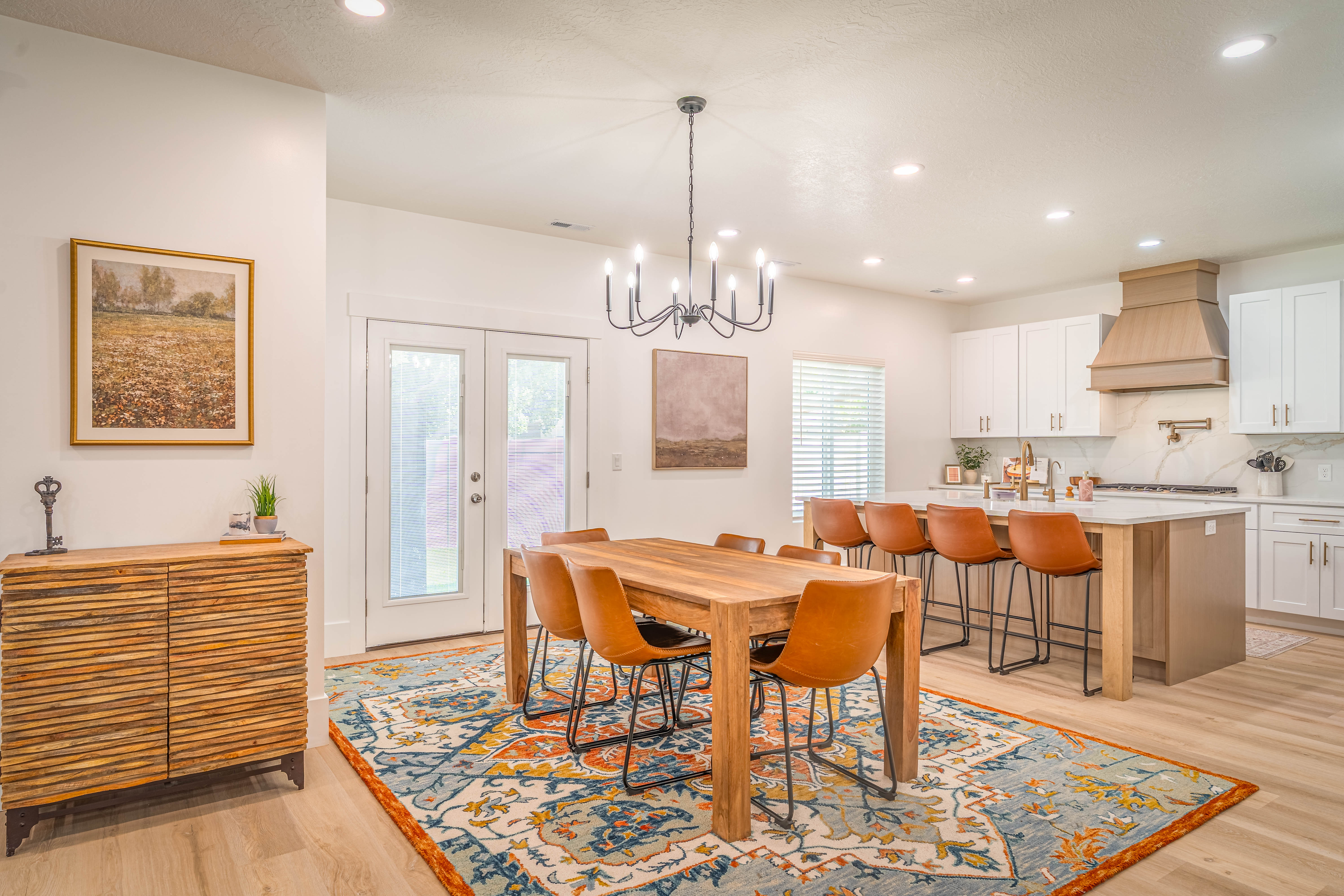 Open-concept dining area featuring a wood-finish dining table with seating for eight, illuminated by a black chandelier