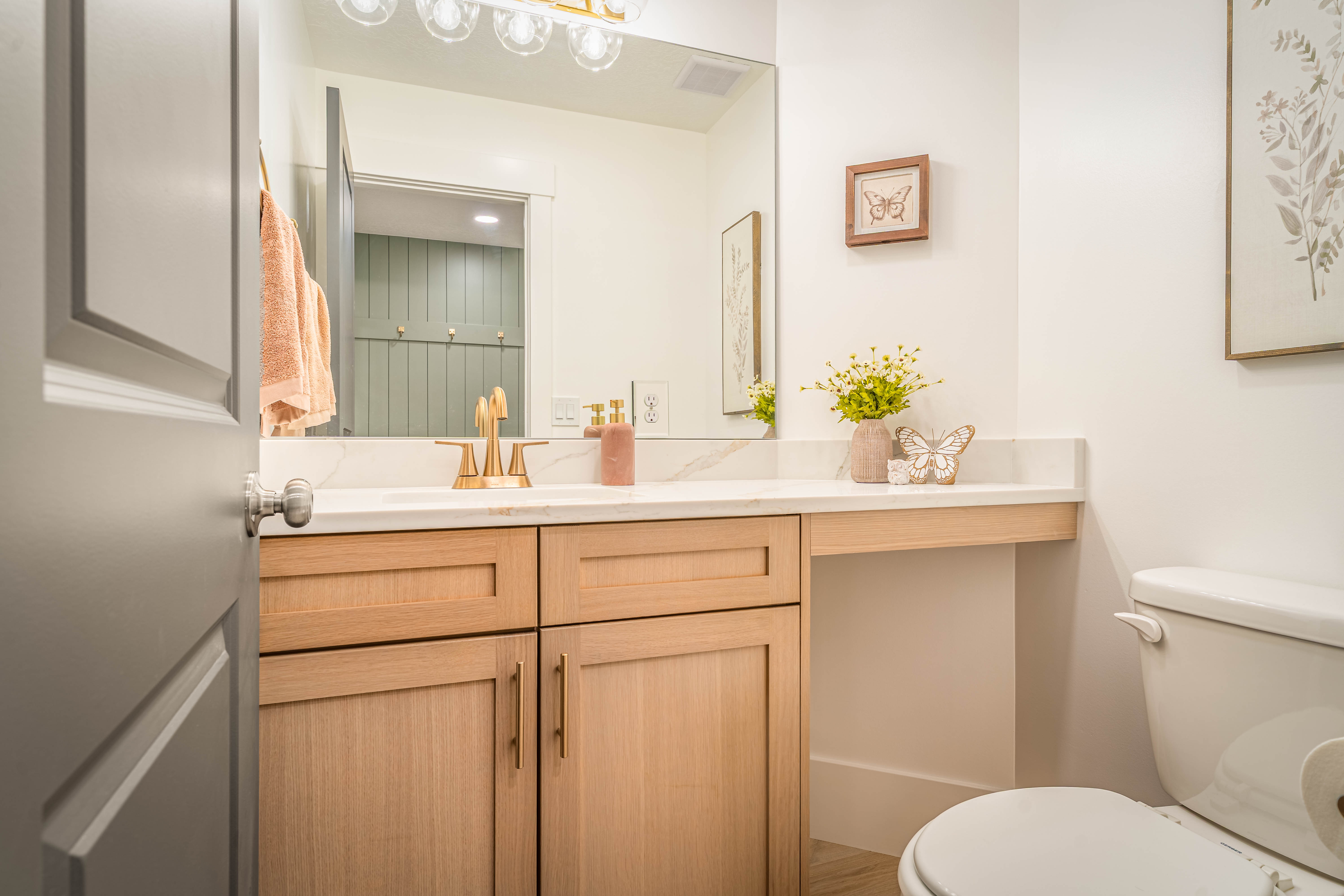 Bathroom featuring a light wood-finish vanity with gold-tone hardware, a white countertop, and a built-in toilet