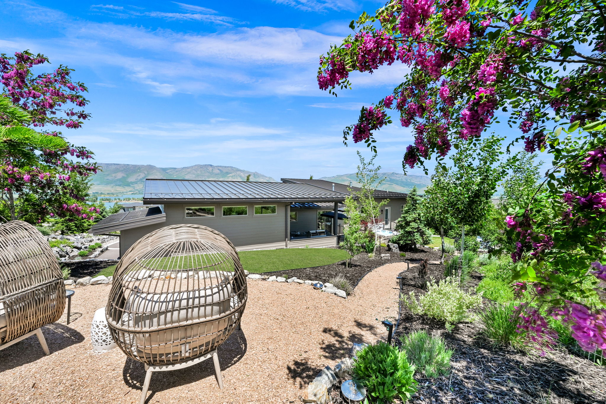 Expansive exterior featuring a gravel pathway, diverse plantings, and a manicured lawn