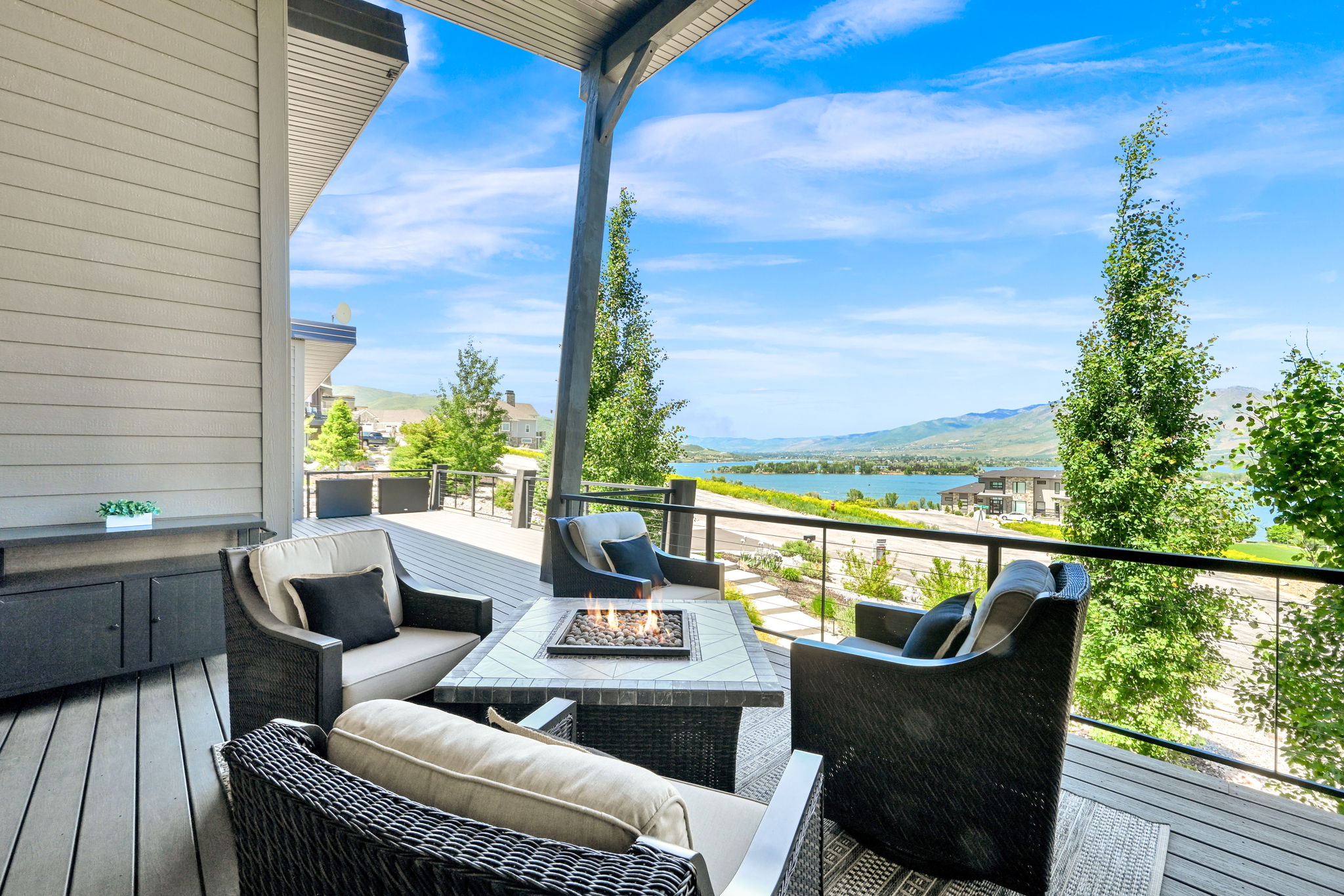 Spacious covered deck featuring composite decking, a built-in fire pit, and glass panel railings