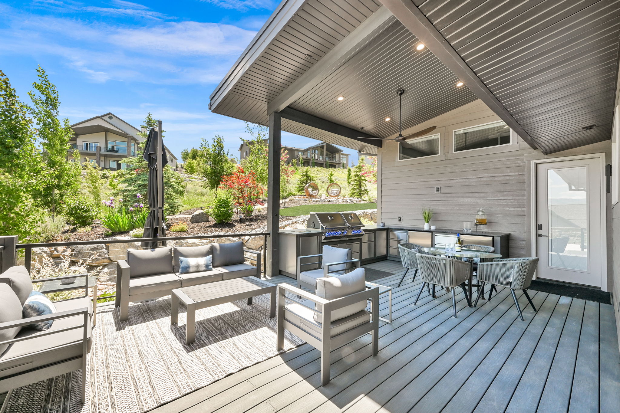 Spacious covered deck featuring composite decking, ceiling fan, recessed lighting, and an outdoor kitchen area with a built-in grill