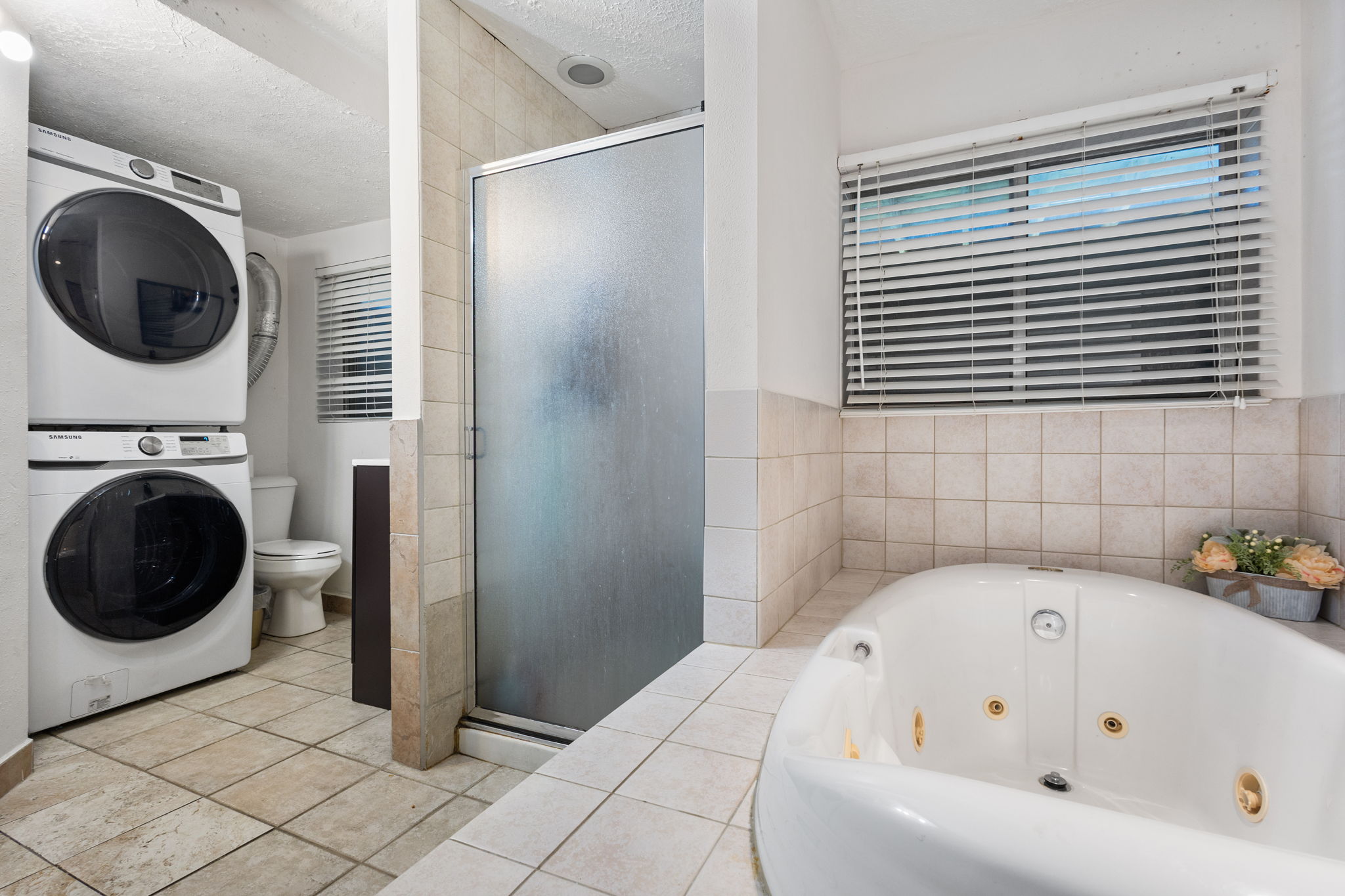 Bathroom featuring a built-in jetted tub, a tiled shower enclosure with frosted glass, and ceramic tile flooring