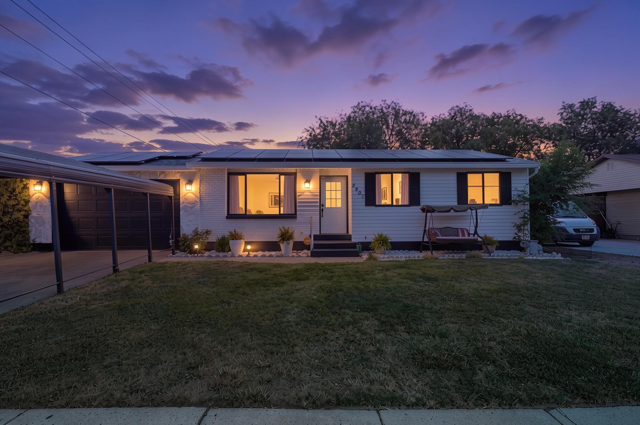 Ranch-style exterior featuring white siding with black trim, a covered carport, and multiple solar panels