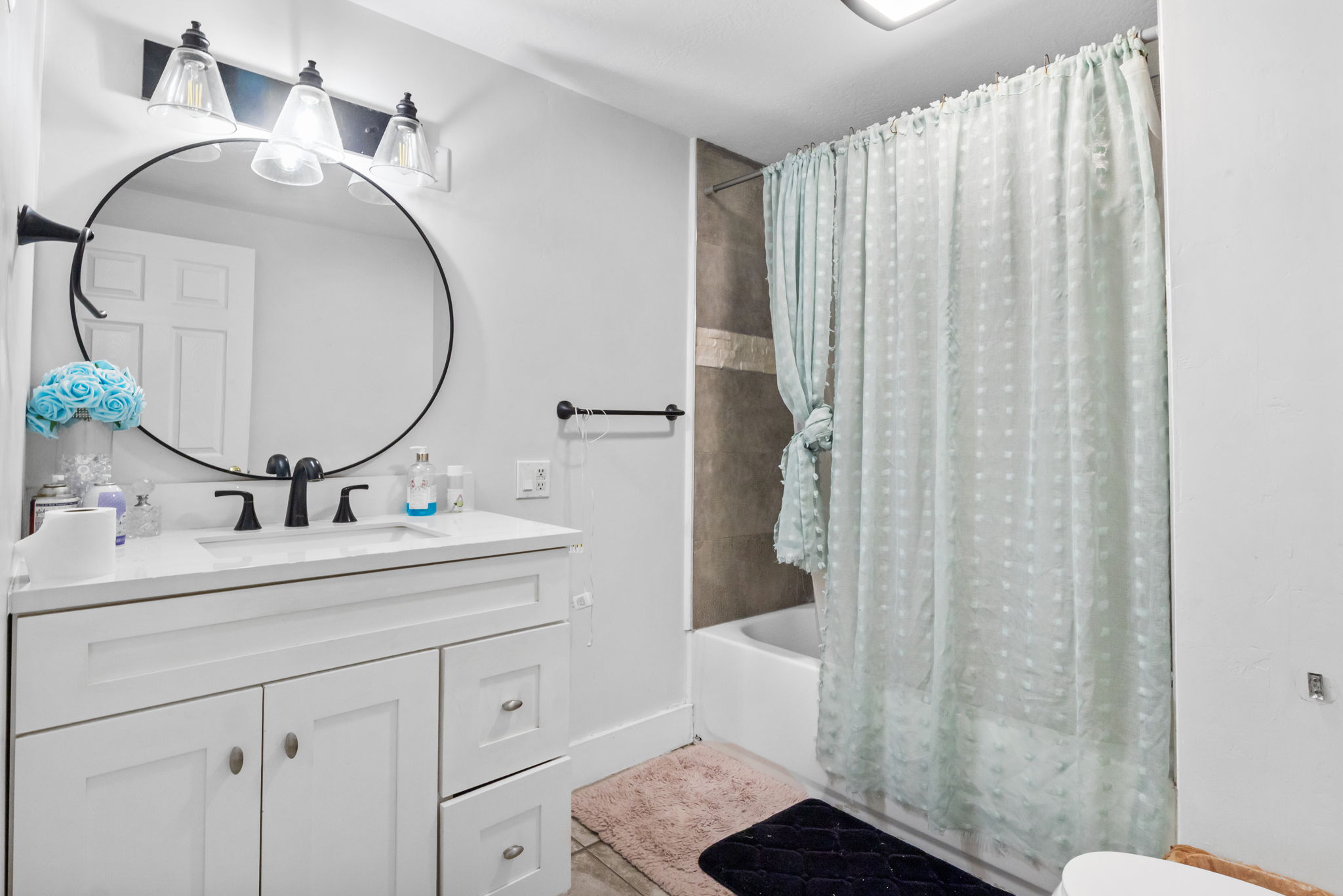 Modern bathroom featuring a white vanity with a rectangular sink and matte black faucet