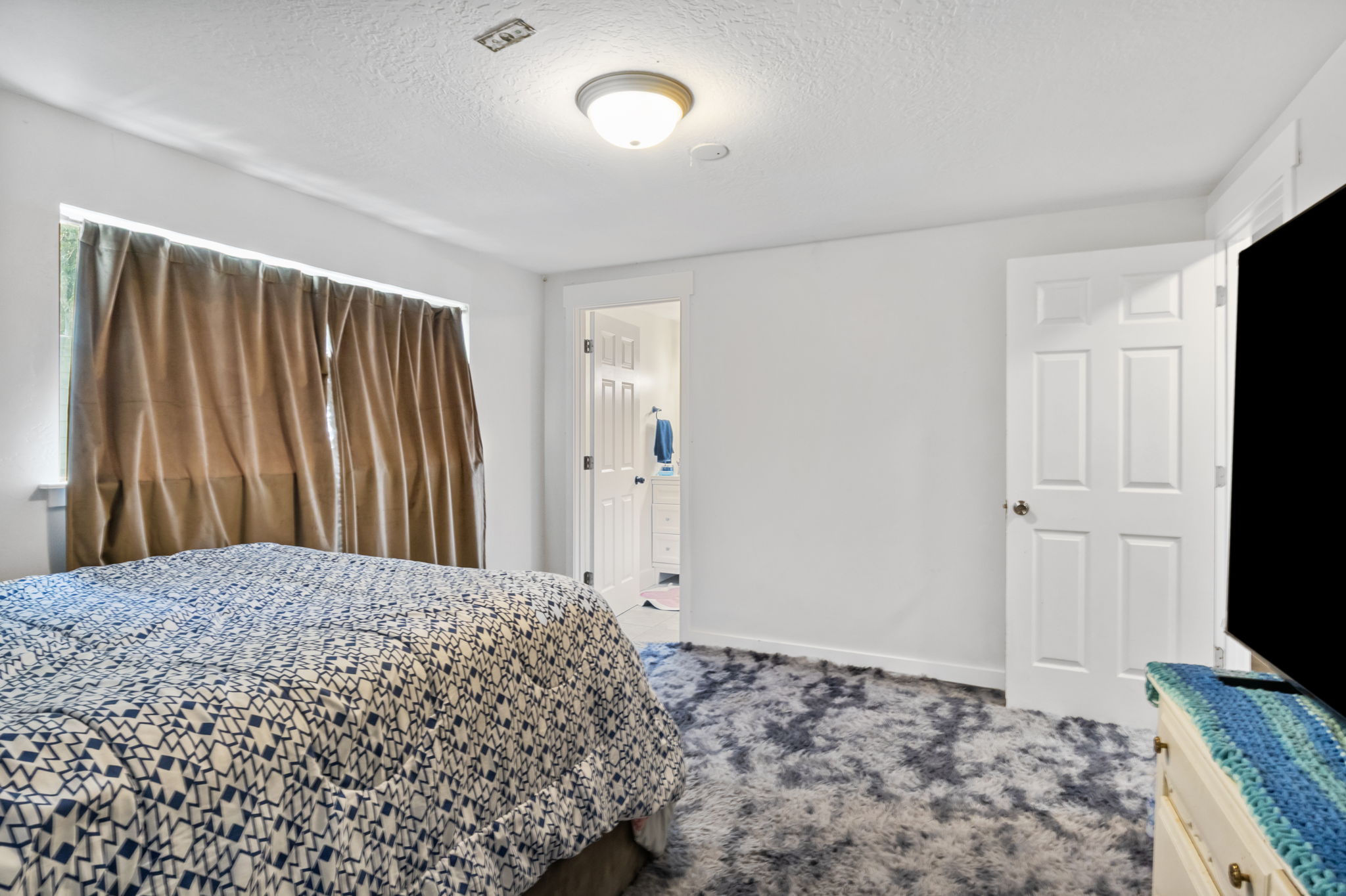 Spacious room with plush gray and white patterned carpeting, white walls, and a large window