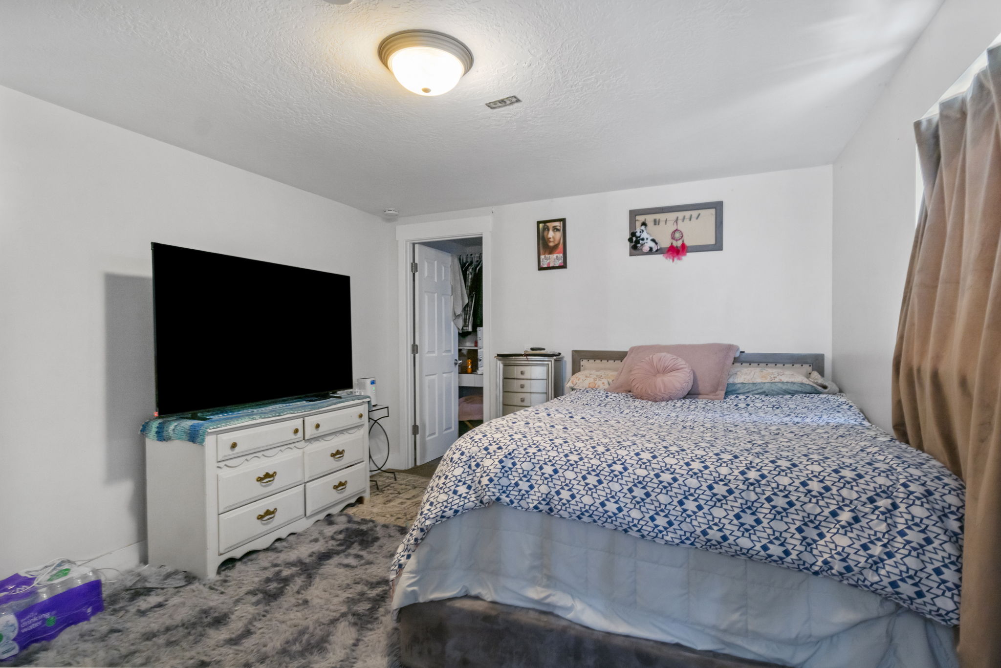 Bedroom featuring a neutral color palette, ceiling-mounted light fixture, white walls, and a visible closet entry with a white paneled door
