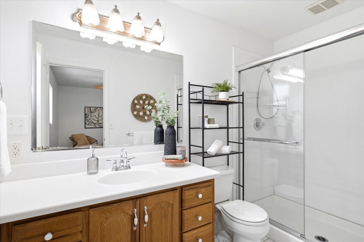Bathroom featuring a single vanity with wood cabinetry, a white countertop, and a large mirror