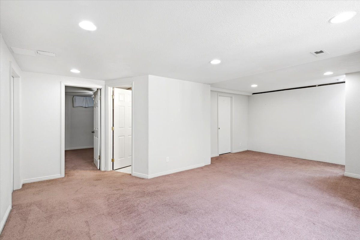 Spacious room featuring neutral carpeting, recessed lighting, and white walls