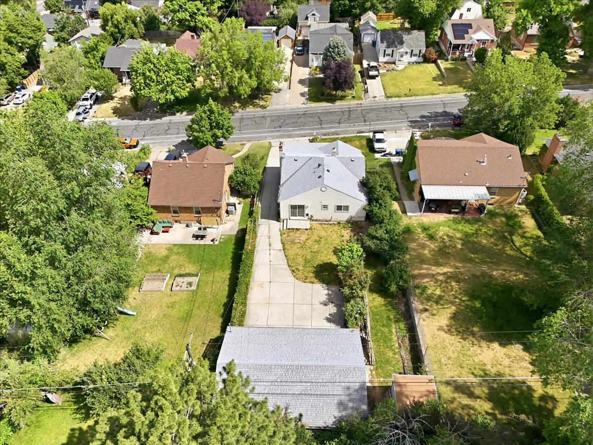 Expansive lot featuring a single-story residence with a light-colored exterior and a gray-shingled roof