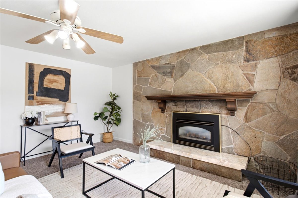 Stone fireplace featuring a decorative wood mantel and a gas insert