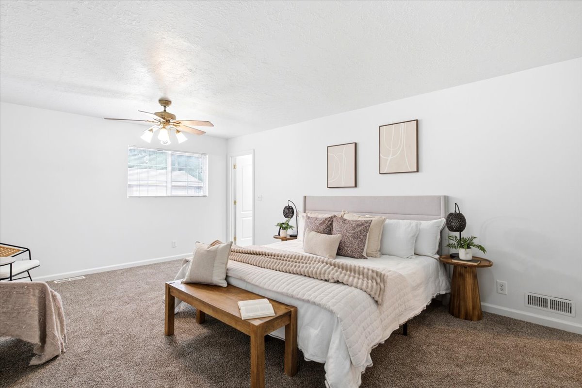 Spacious room featuring neutral carpeting, white walls, and a ceiling fan with integrated lighting