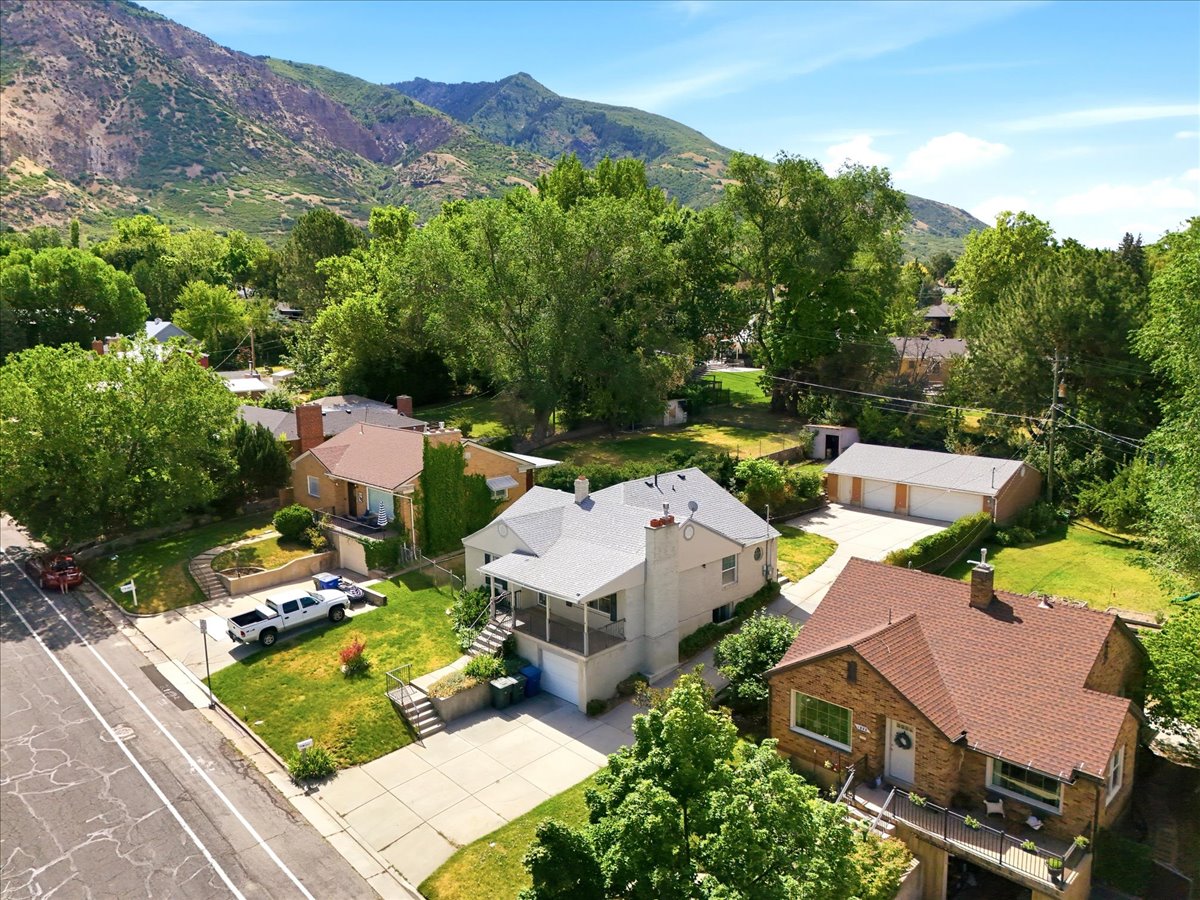 Aerial perspective showcasing a light-colored home with a covered front porch and a detached three-car garage