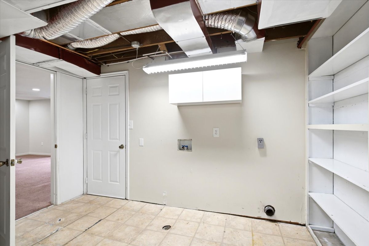 Laundry area featuring tile-finish flooring, built-in shelving, white wall cabinetry, and an exposed ceiling with ductwork