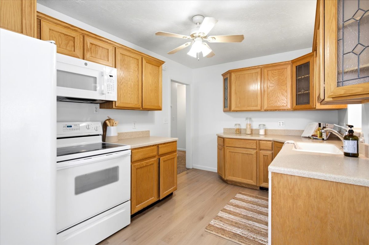 Kitchen featuring light wood cabinetry with display doors, light-toned countertops, and wood-finish flooring
