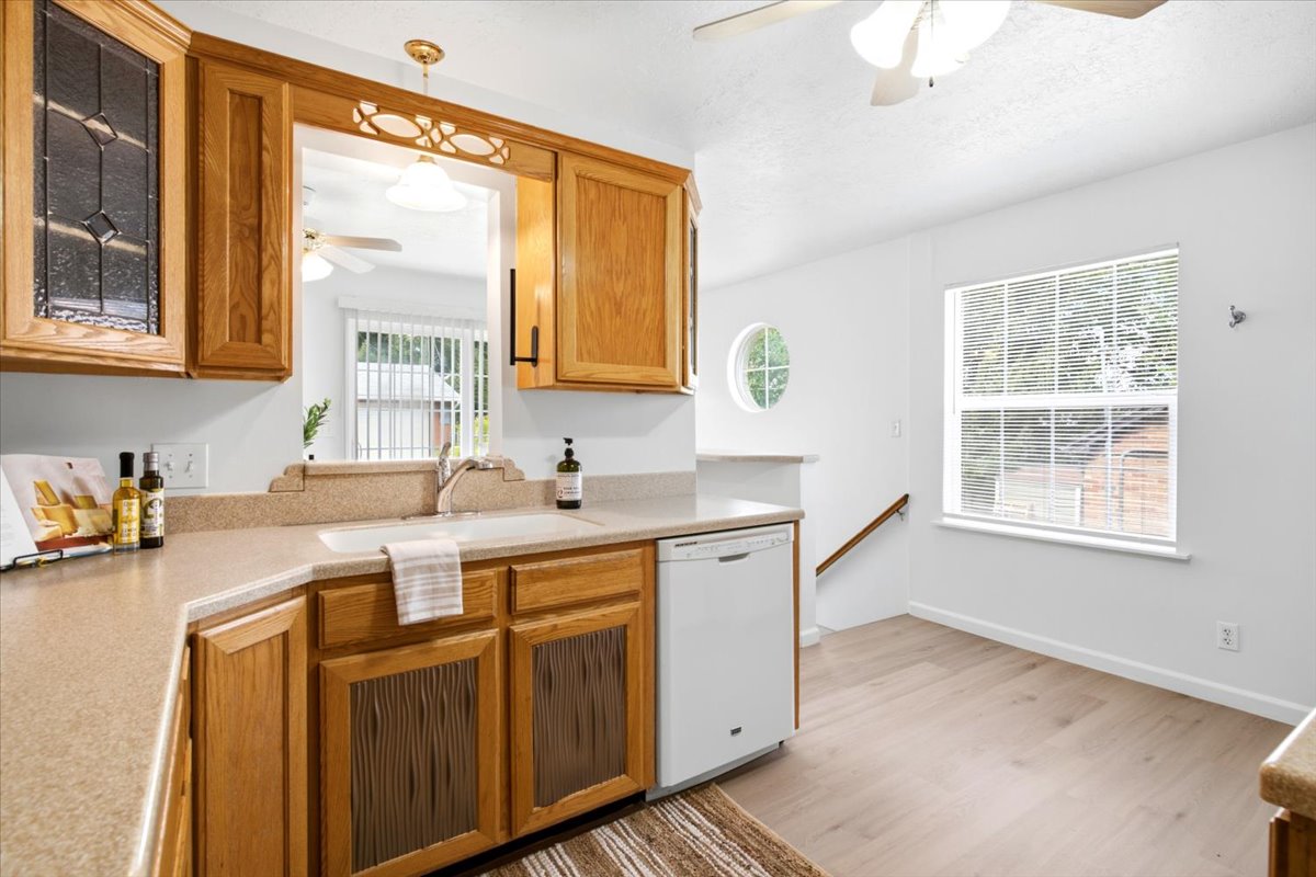 Kitchen featuring wood cabinetry, a pass-through window, and a built-in dishwasher