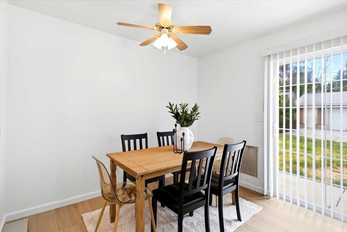 Dining area with light wood-finish flooring, white walls, and a ceiling fan with integrated lighting