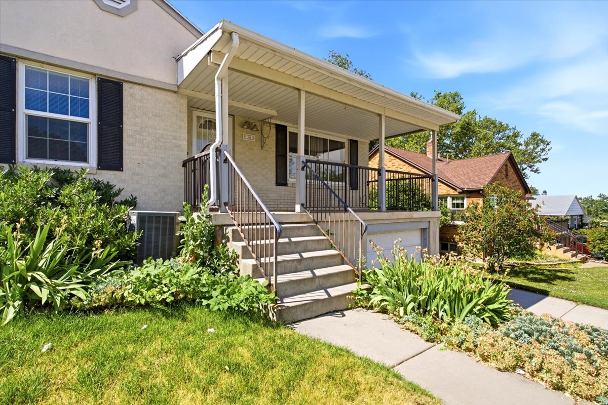 Covered front porch with concrete steps and metal railings
