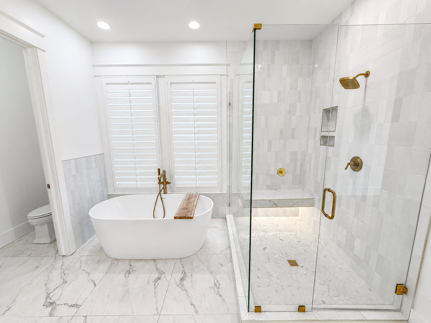 Soaking tub, glass-enclosed shower with rain head and built-in shower bench