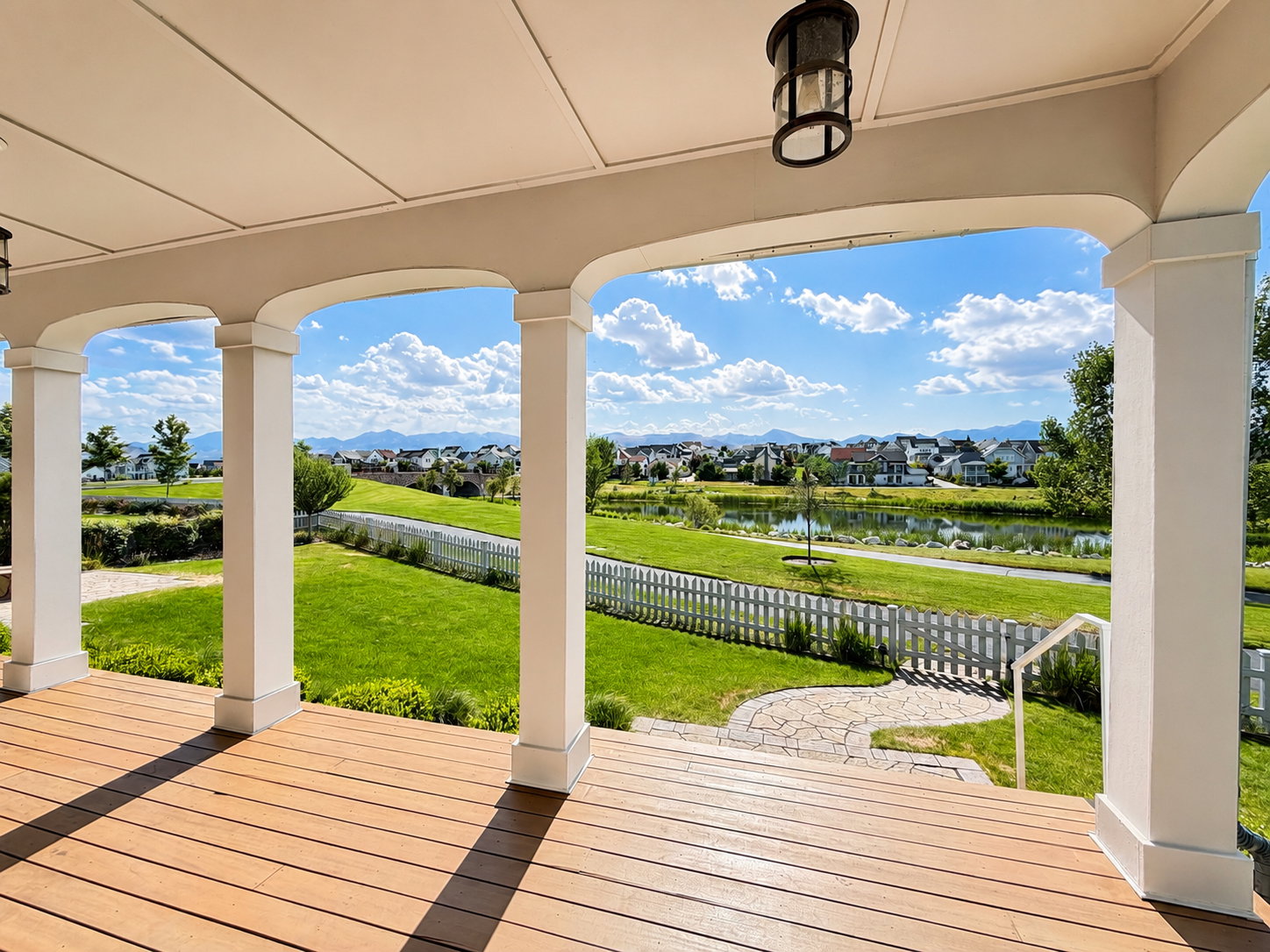 Full length covered porch with wood-finish decking, supported by architectural columns with arched soffits