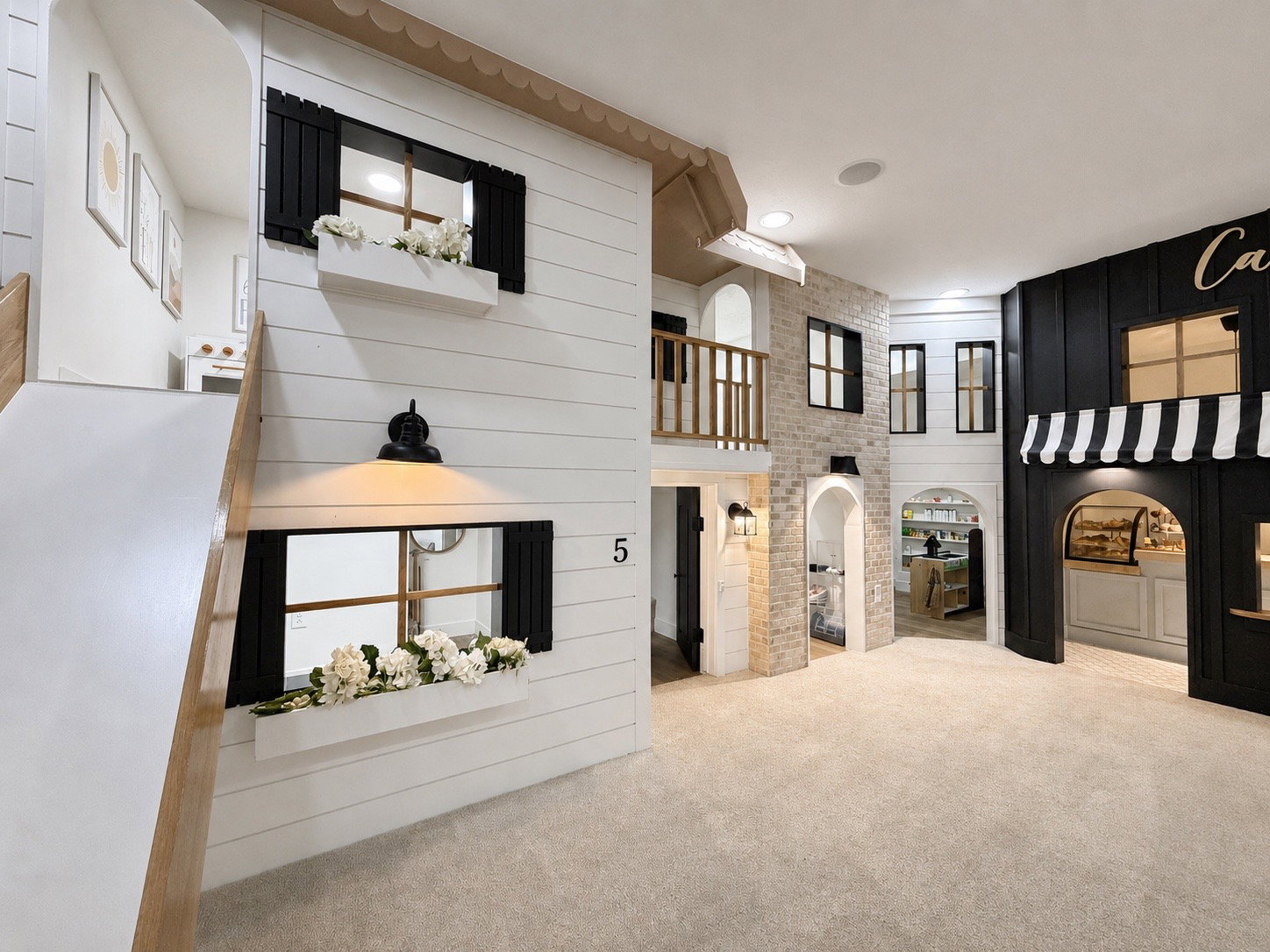 5 Pretend City Lane, a custom-built interior play structure featuring varied facades, decorative window boxes, wall-mounted light fixtures, an upper-level balcony and functioning slide