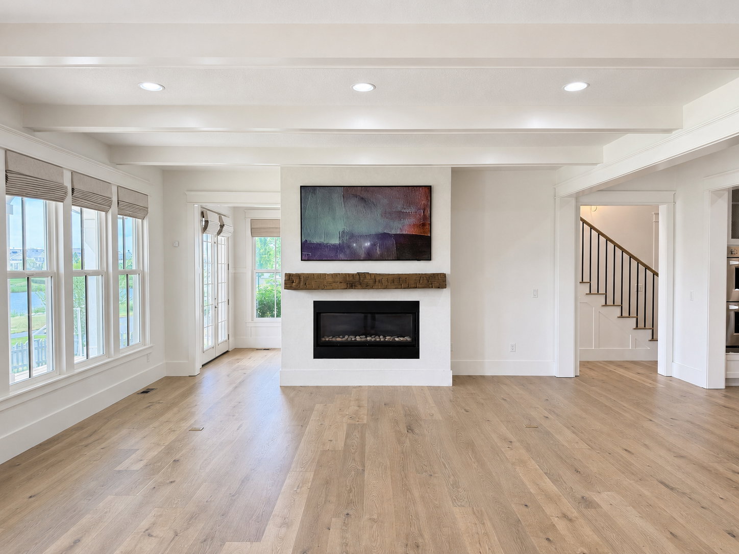 Large gathering area with engineered wood flooring, Venetian plaster fireplace with rustic wood mantle and ceiling beams