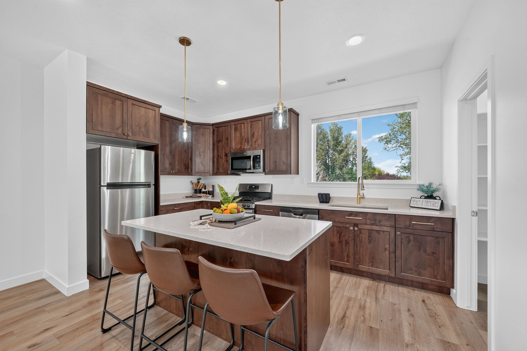 Contemporary kitchen featuring wood-finish flooring, dark wood cabinetry, and stainless steel appliances