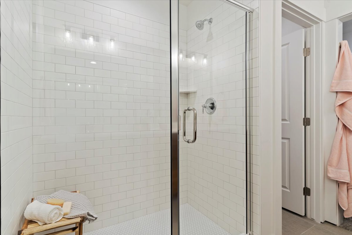 Glass-enclosed shower featuring white subway tile walls and a hexagonal tile floor
