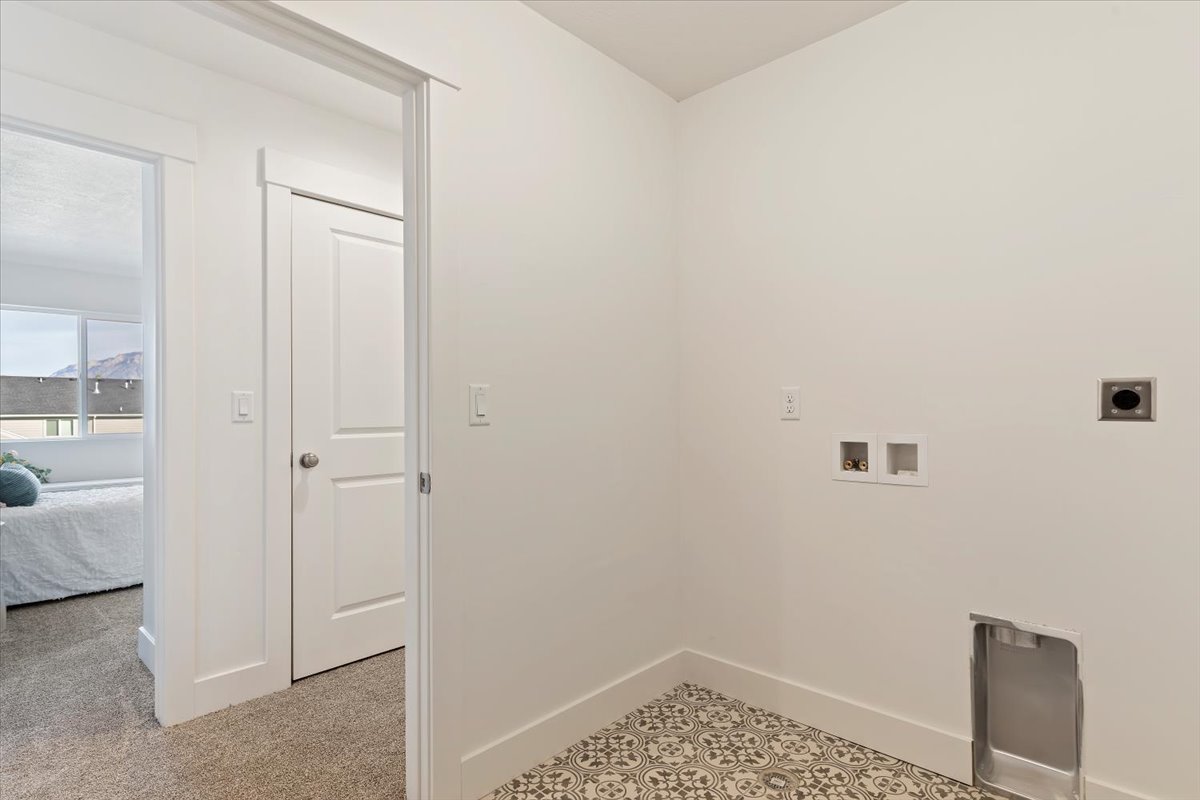 Dedicated laundry area featuring patterned floor tile, white wall finishes, and all necessary hookups for appliances