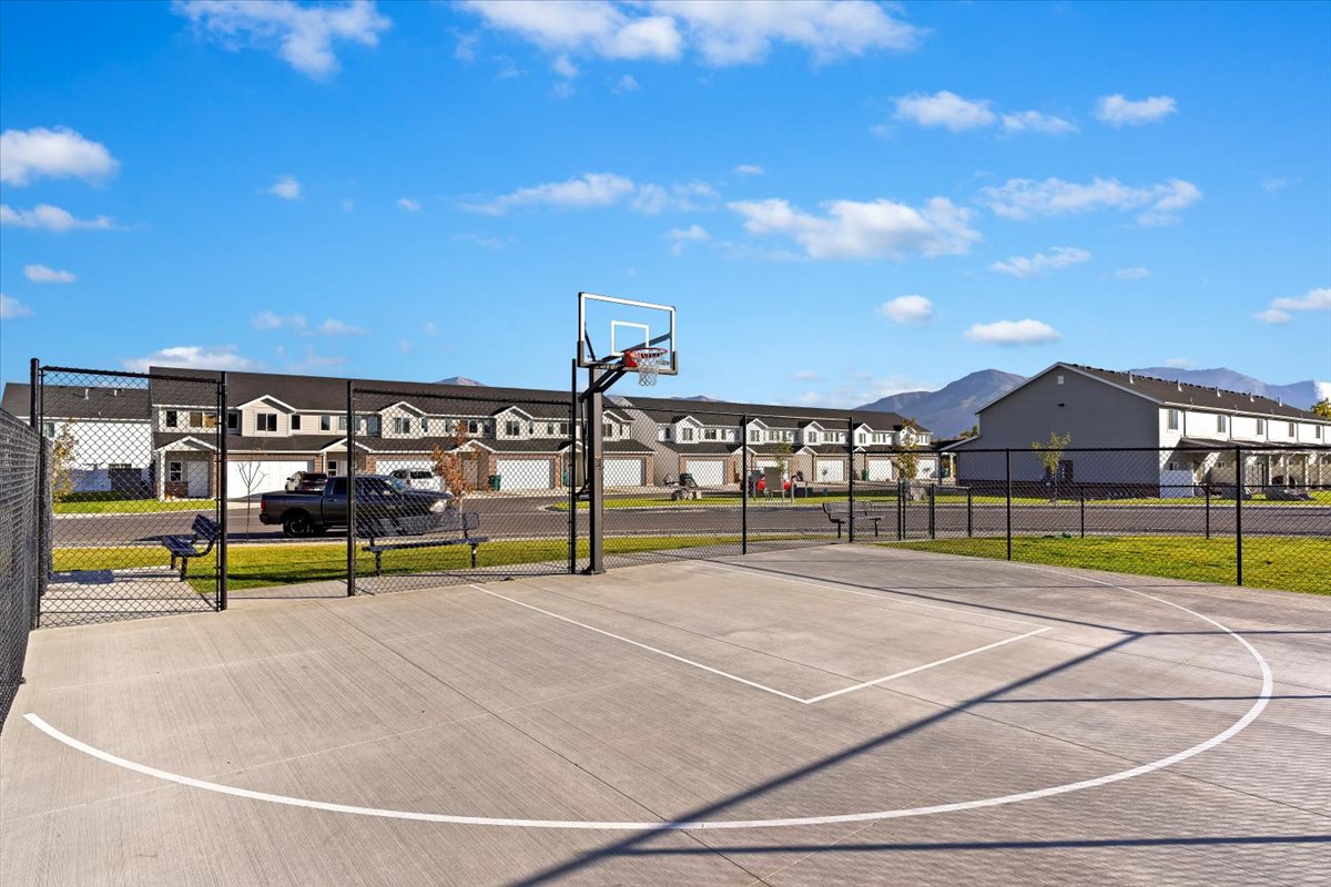 Concrete sports court with a basketball hoop and chain-link fencing