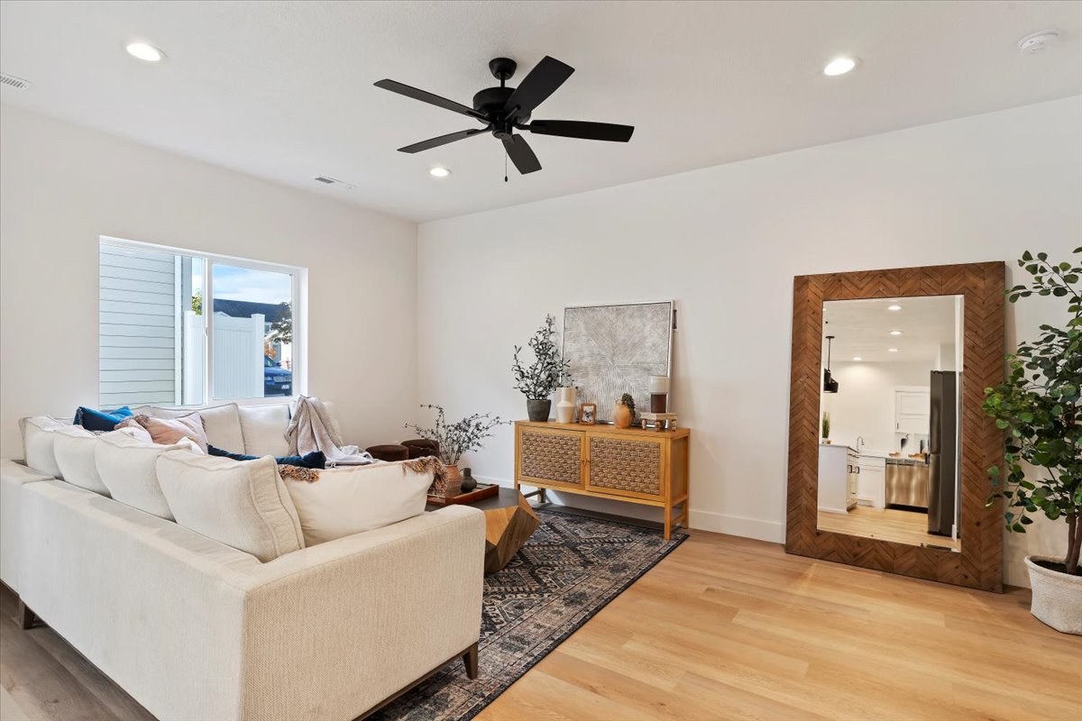 Bright living area featuring light wood-finish flooring, recessed lighting, and a modern ceiling fan