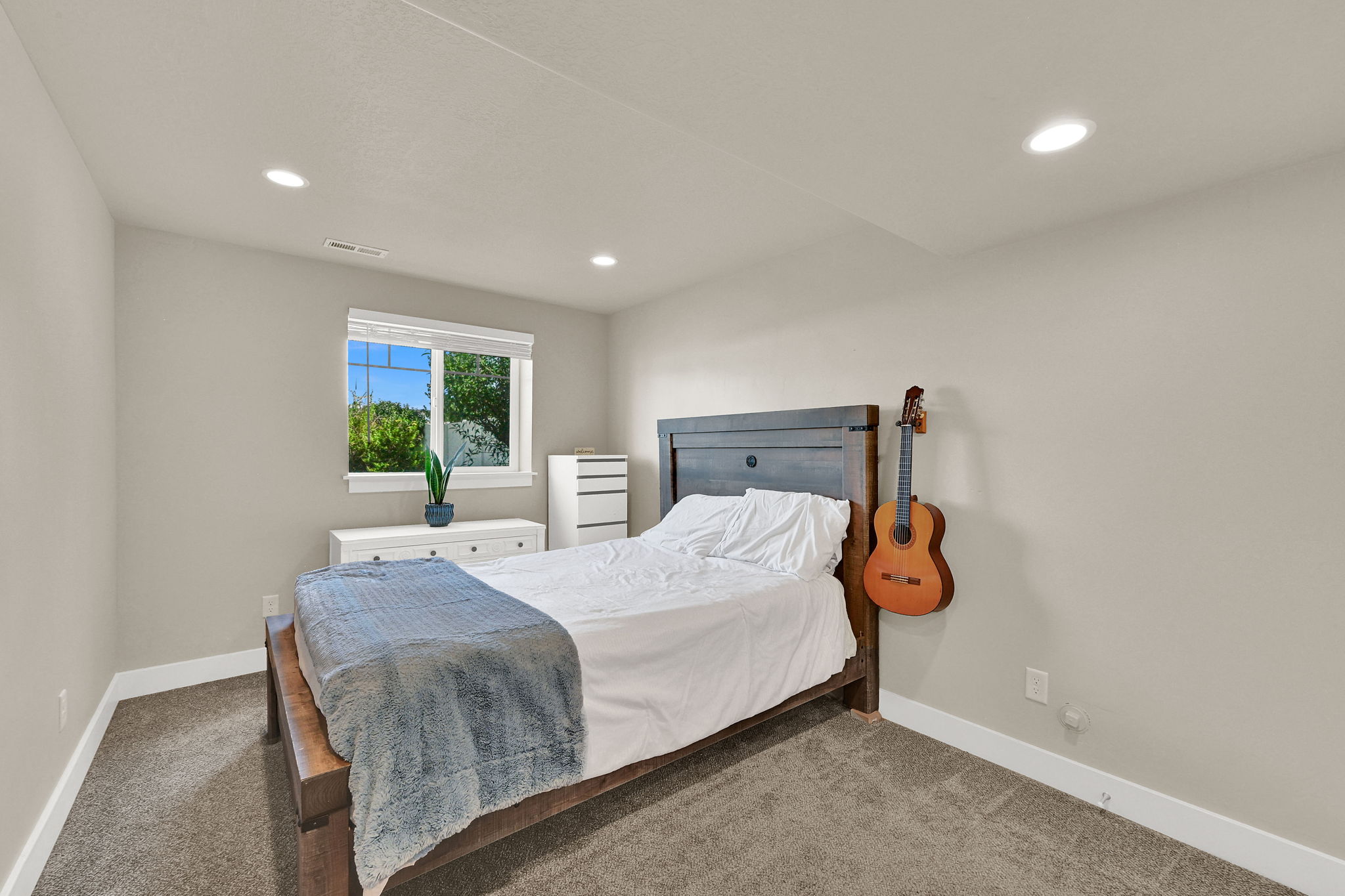 Carpeted room featuring a large window with white blinds, recessed ceiling lighting, and a neutral wall color