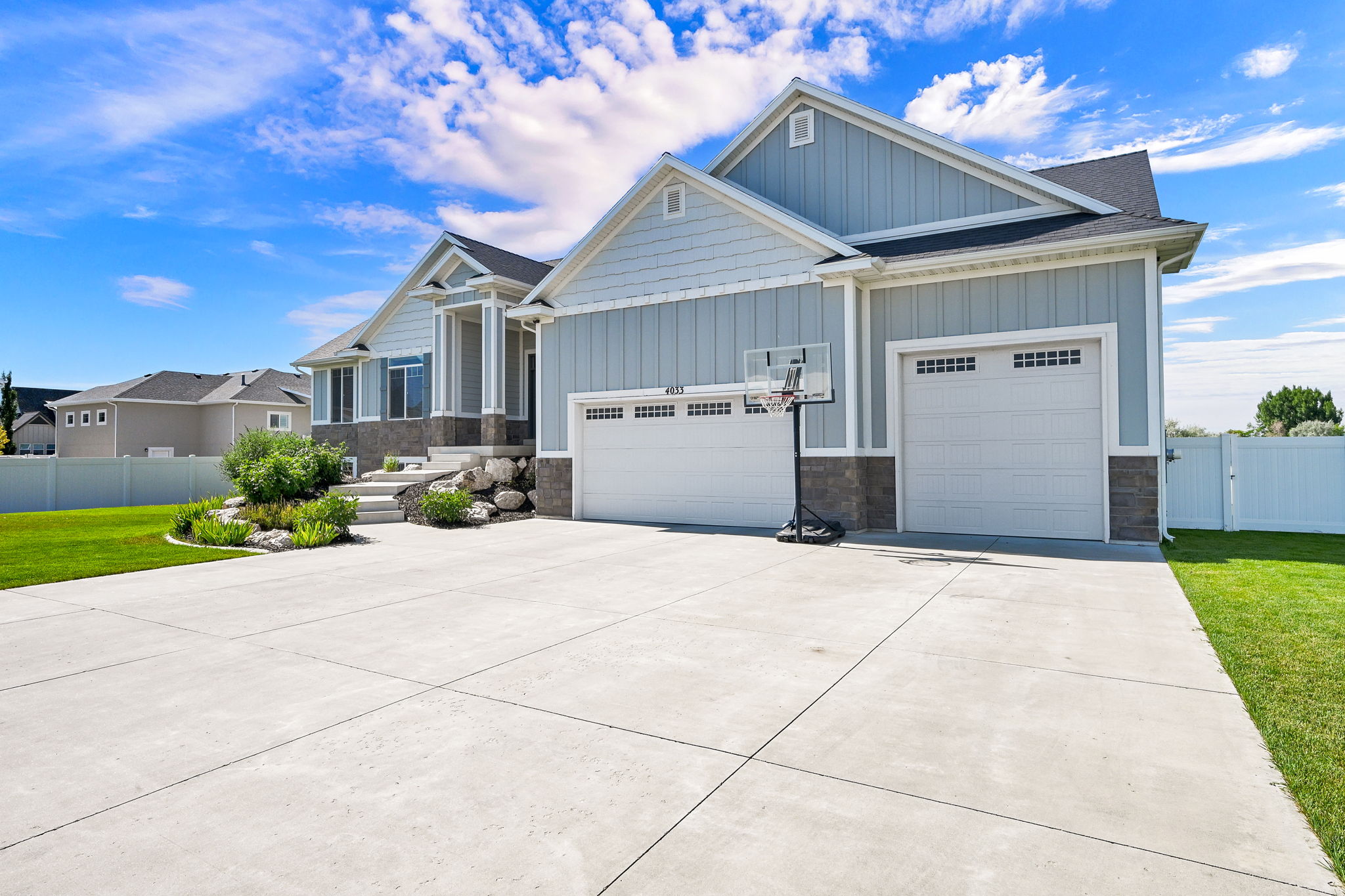Exterior featuring light blue siding, stone accents, and a multi-car driveway