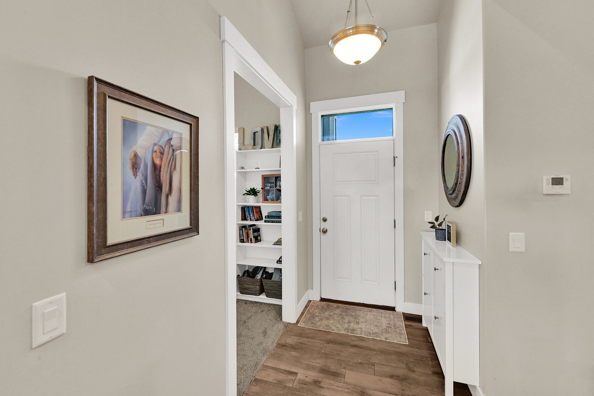 Entryway featuring a white paneled door with transom window, wood-finish flooring, and a built-in shelving unit