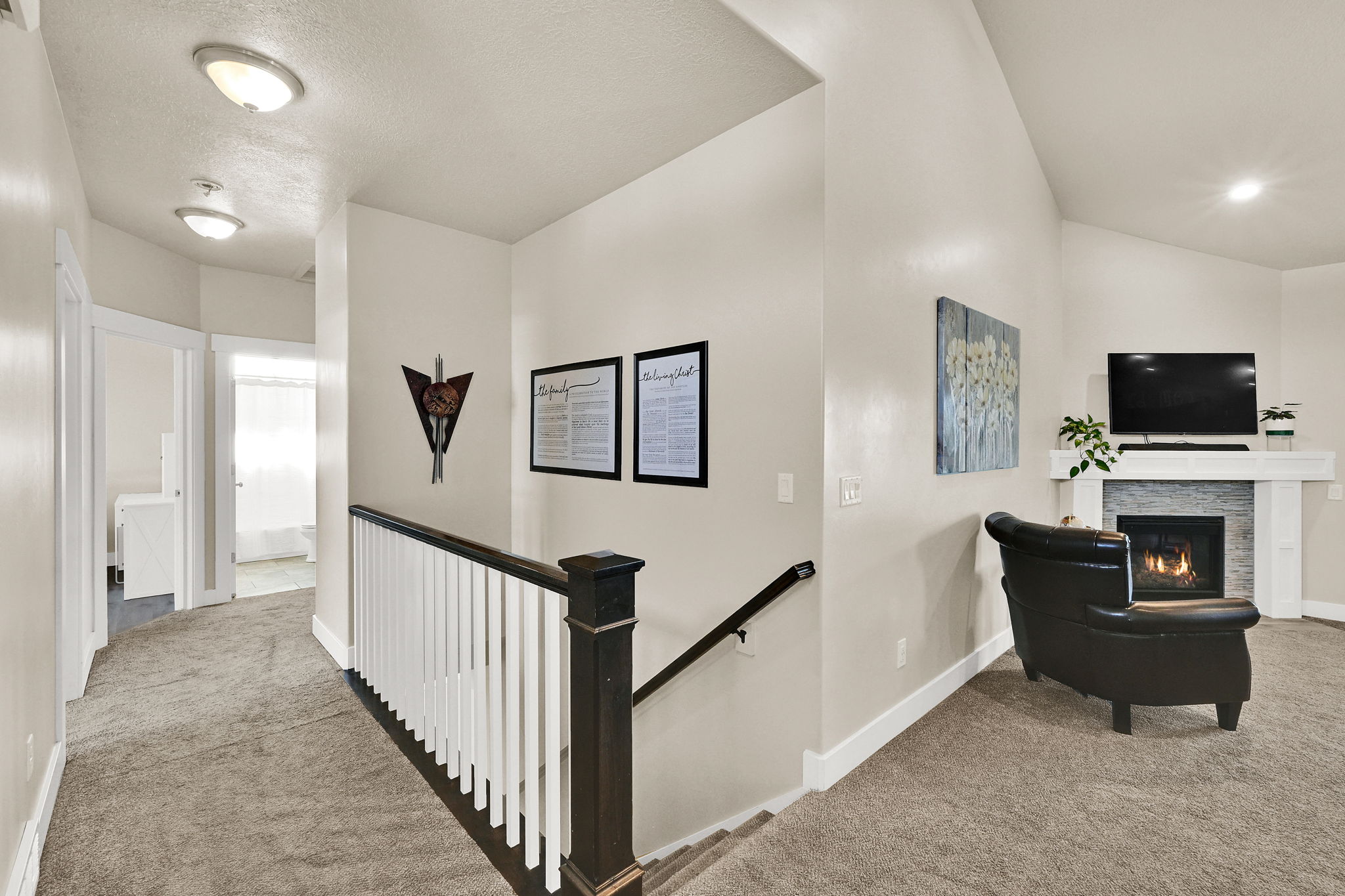 Upper-level landing featuring neutral carpeting, white trim, and a dark wood handrail with white balusters