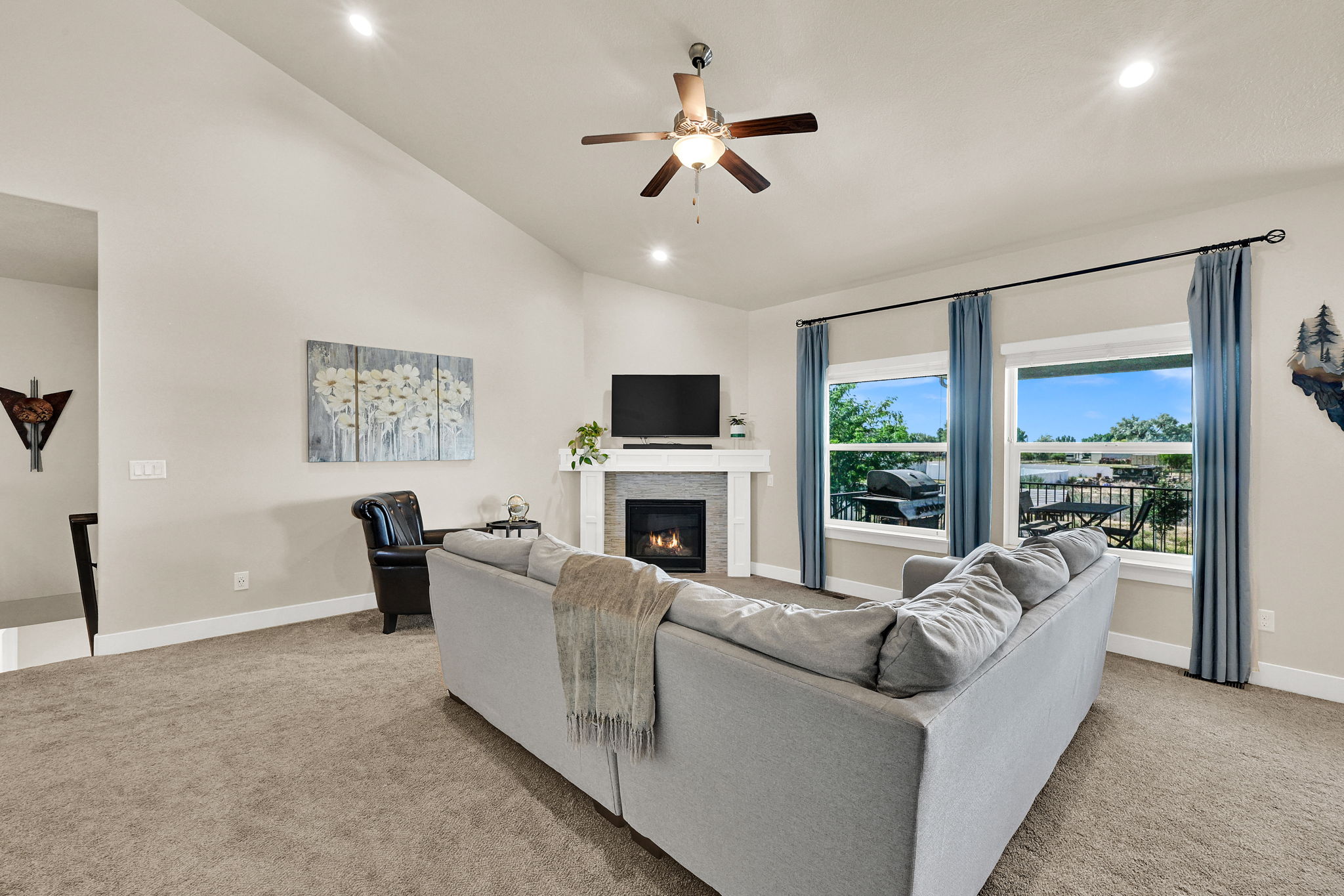 Living area featuring a vaulted ceiling with recessed lighting, a ceiling fan, and a fireplace with a light-colored mantel
