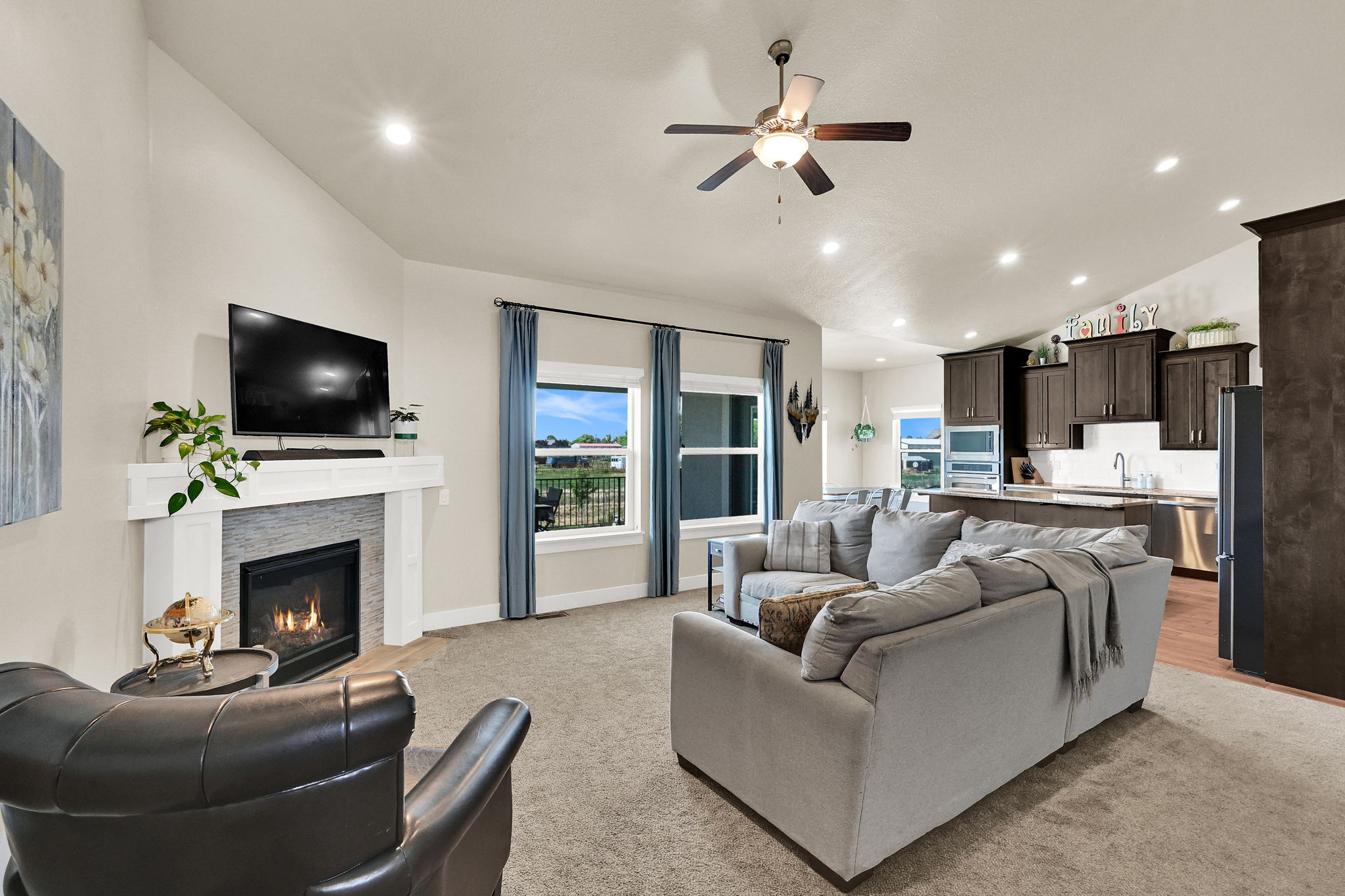 Open-concept living space featuring a living room with a fireplace, vaulted ceilings, recessed lighting, and a ceiling fan