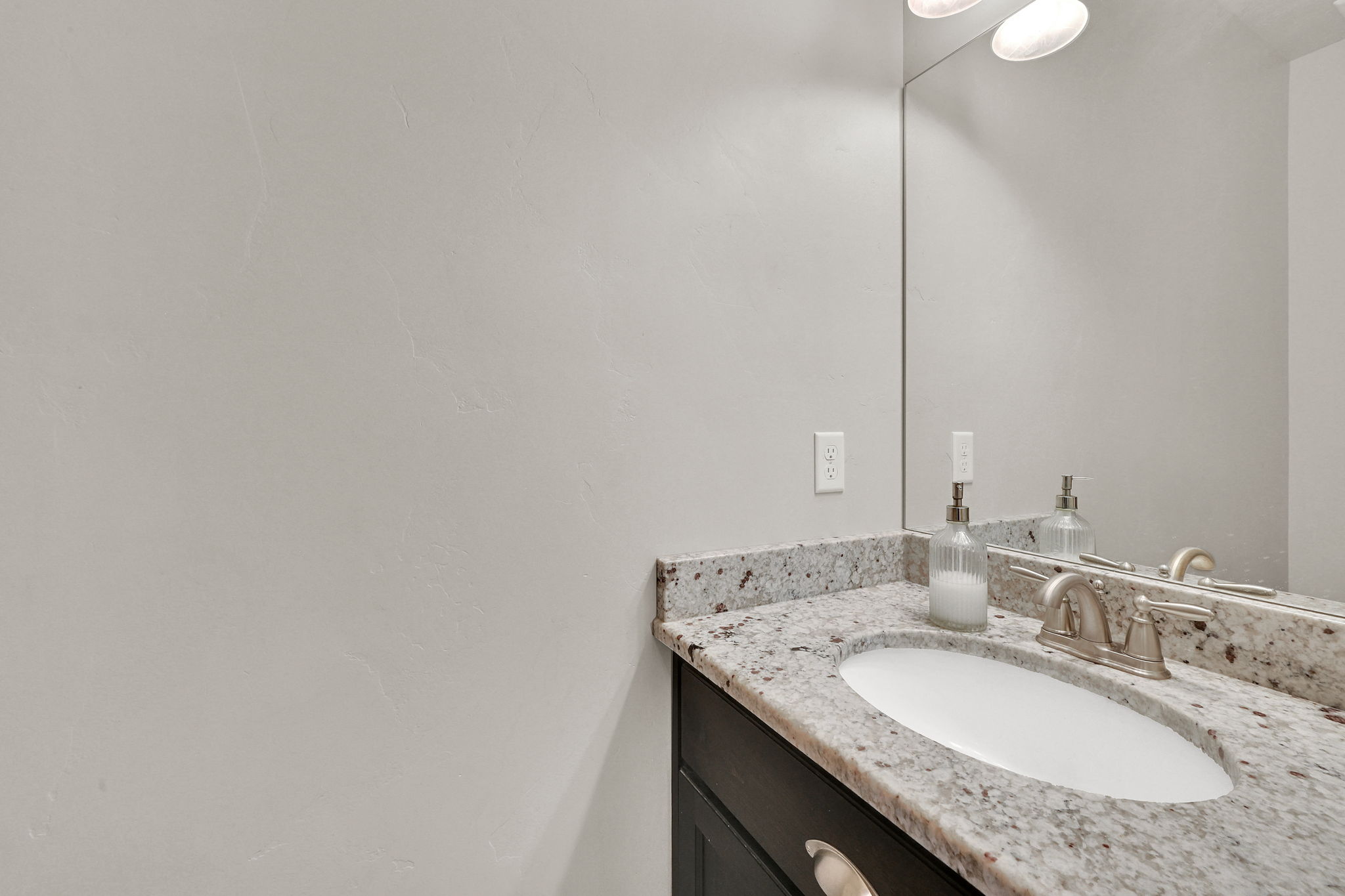 Vanity with a speckled stone countertop, an integrated oval sink, and a brushed nickel faucet