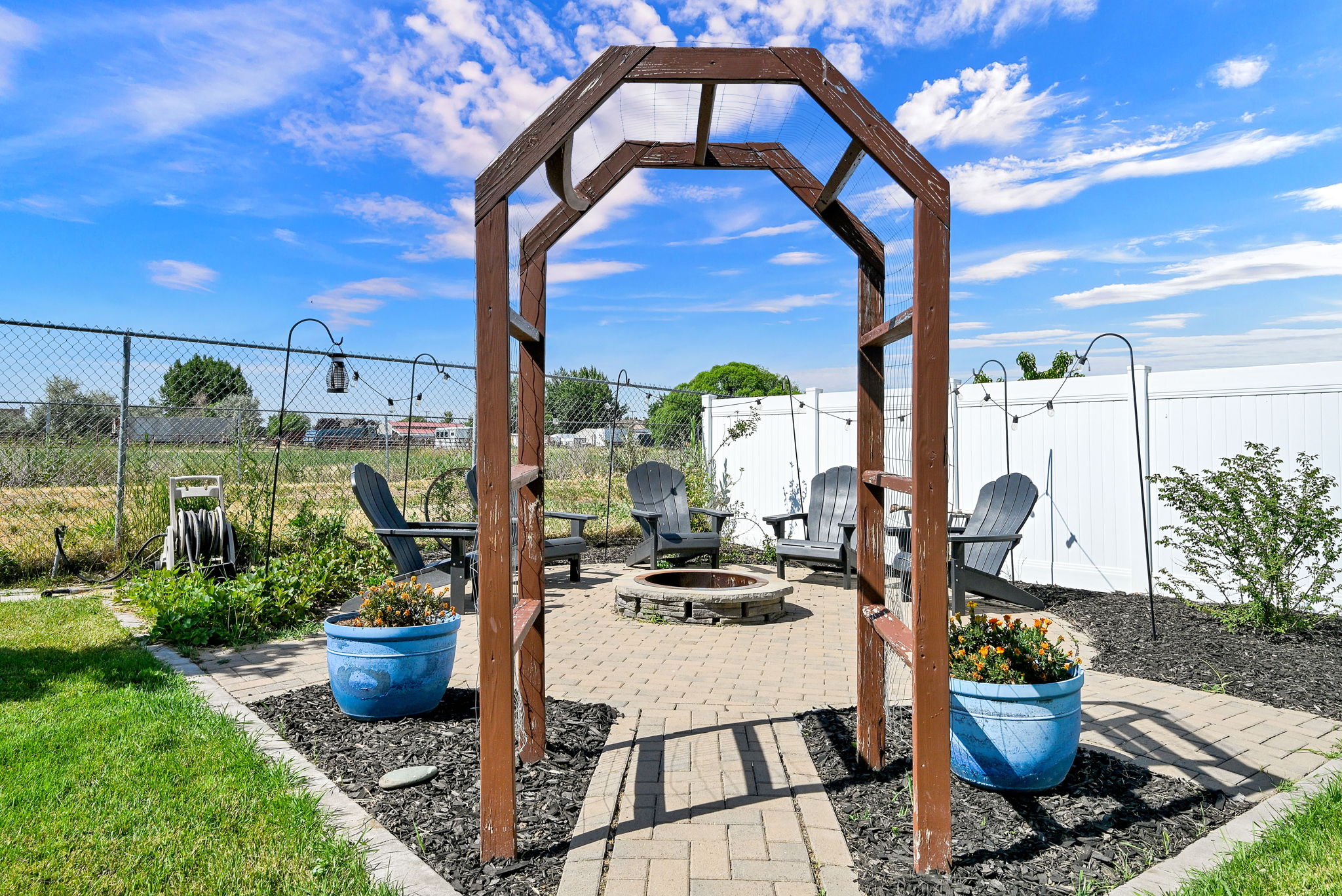 Backyard patio featuring a wood arbor entry and a paver stone seating area