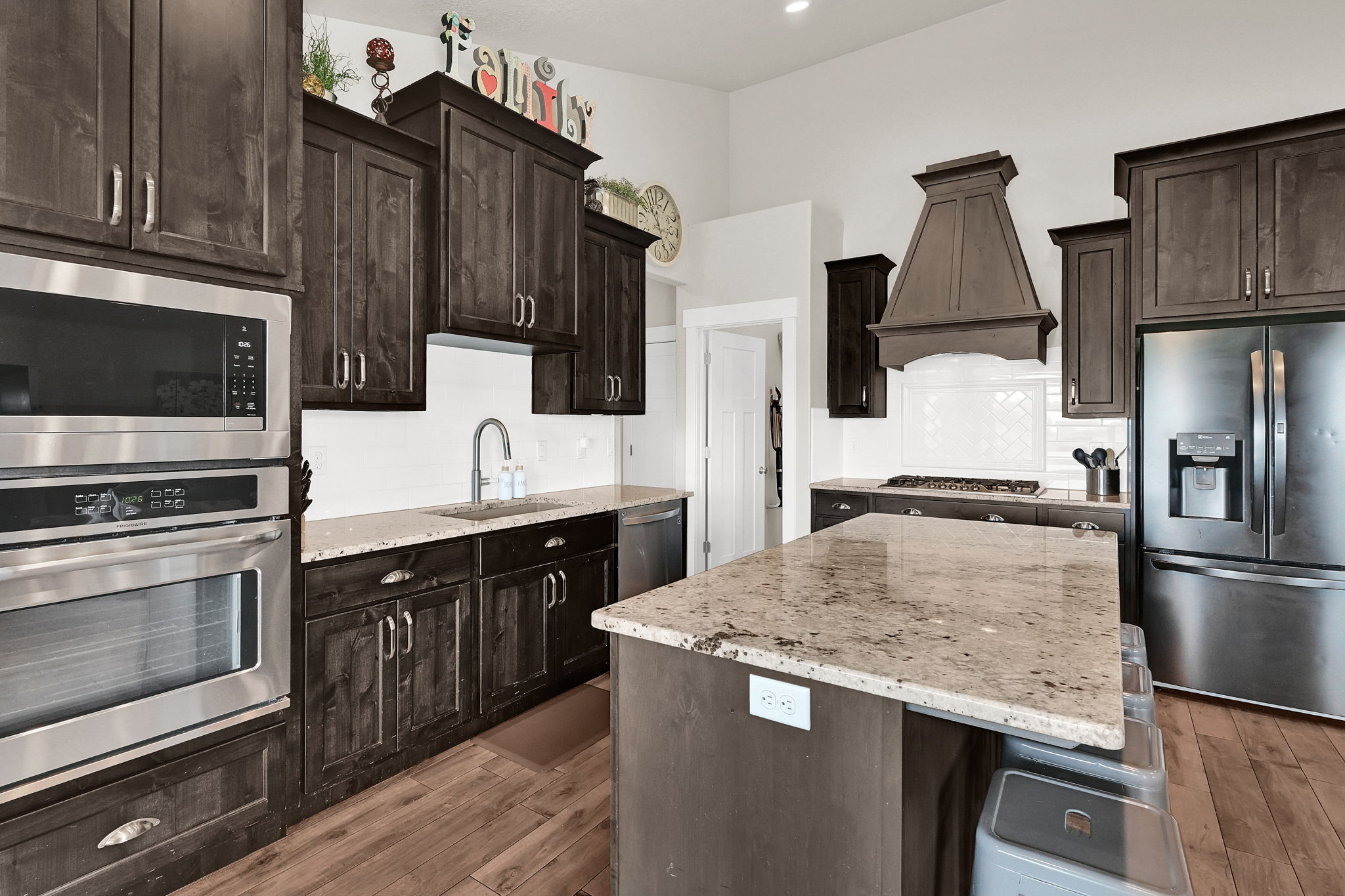 Kitchen featuring dark wood-finish cabinetry, stainless steel appliances, and light-toned stone countertops