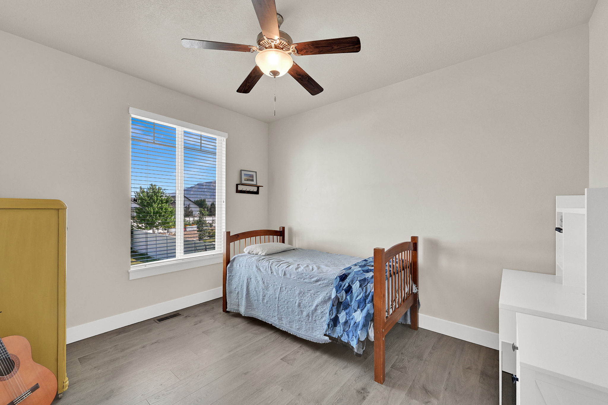 Spacious room featuring a large window, neutral wall tones, and wood-finish flooring