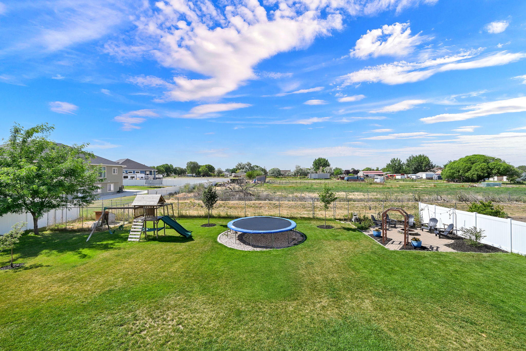 Expansive green lawn with a white privacy fence