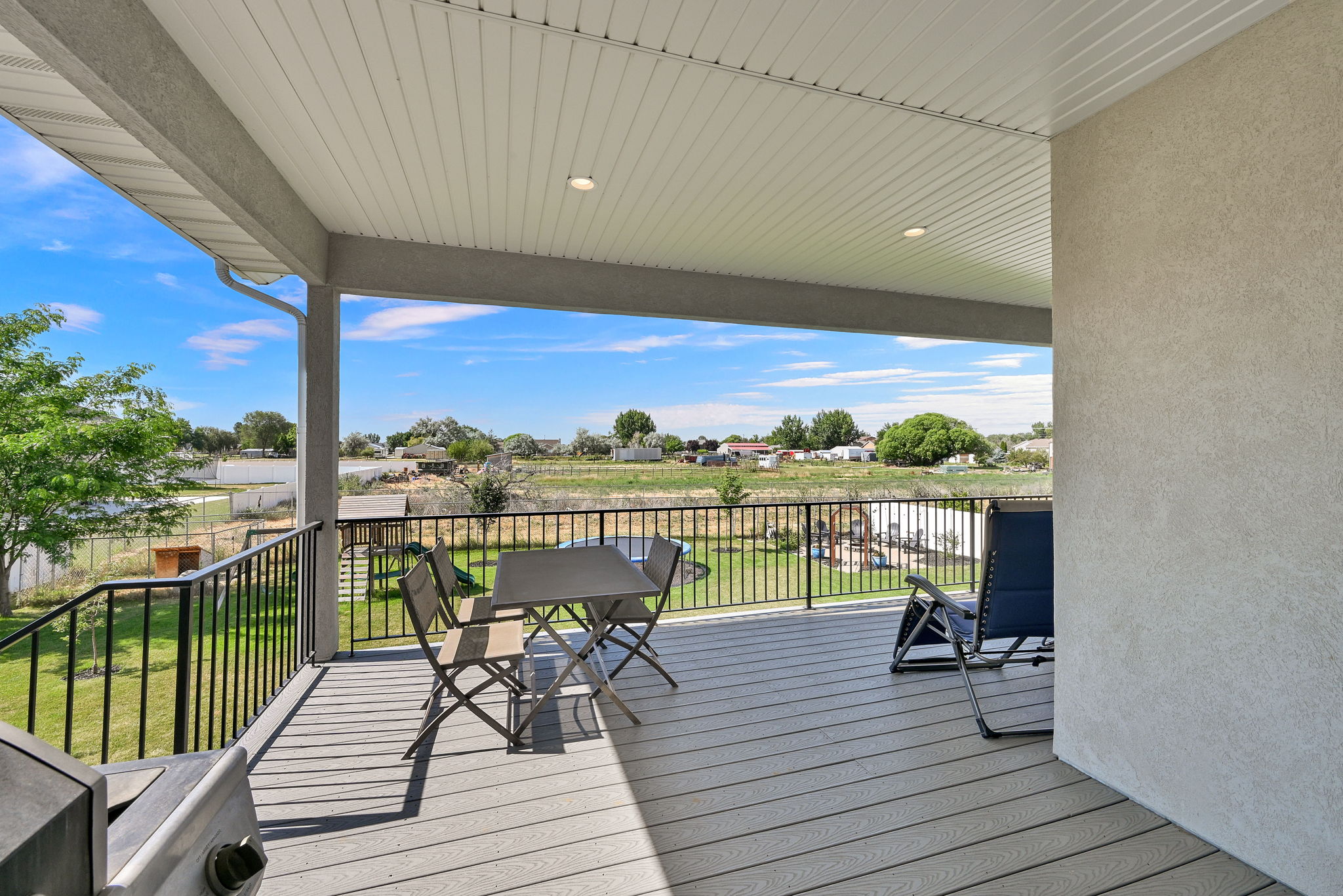 Covered outdoor deck with composite decking, black metal railings, and integrated overhead lighting