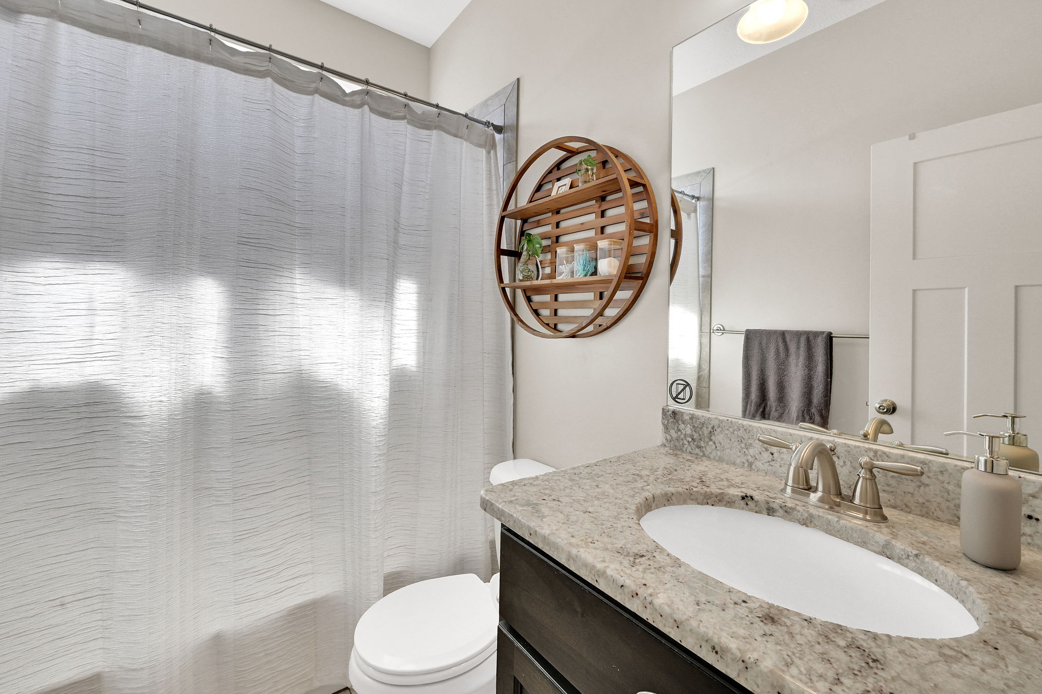 Bathroom featuring a light-toned vanity with an undermount sink, a flecked countertop, and a brushed nickel faucet