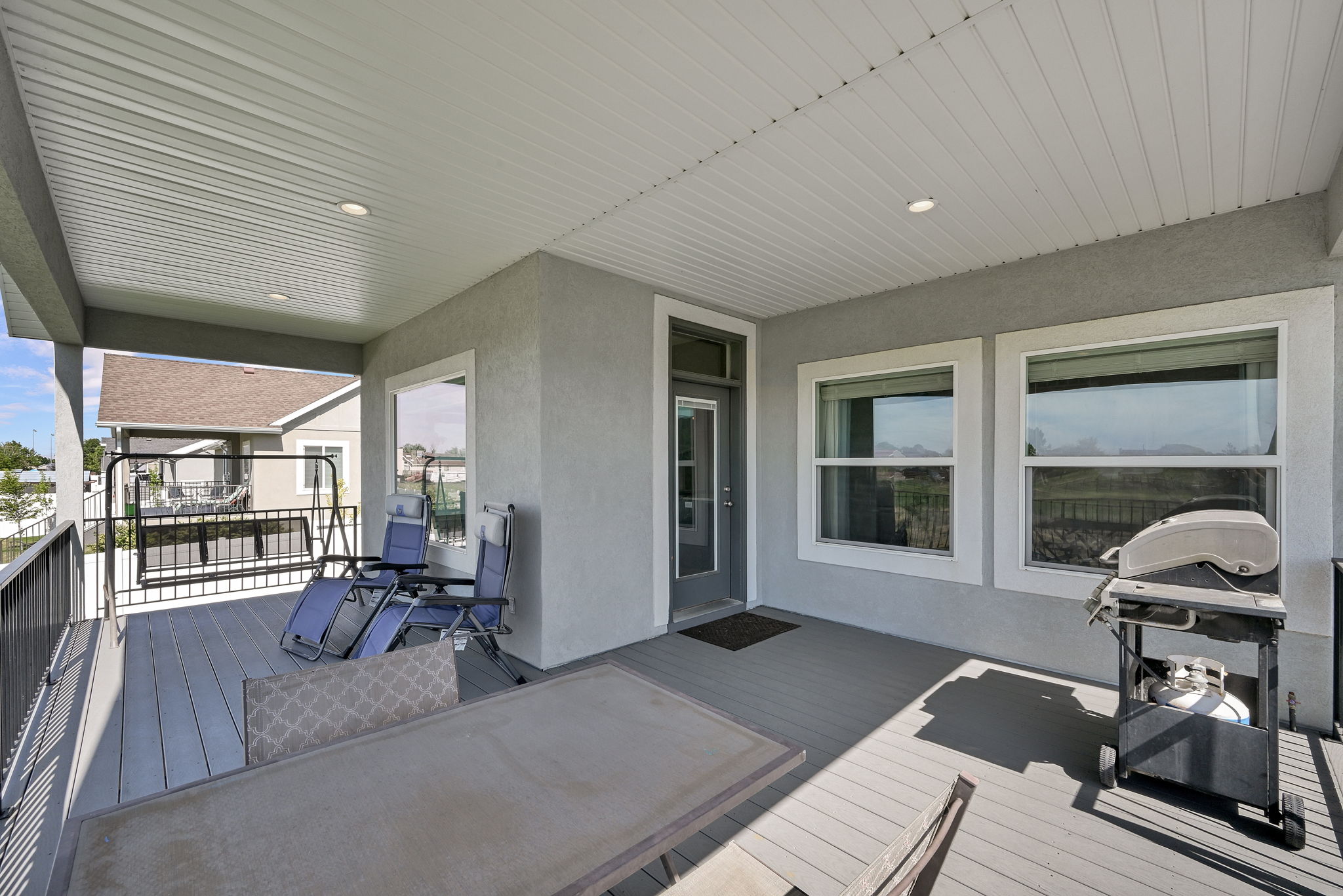 Covered outdoor deck featuring composite decking, recessed lighting, and a stucco exterior finish