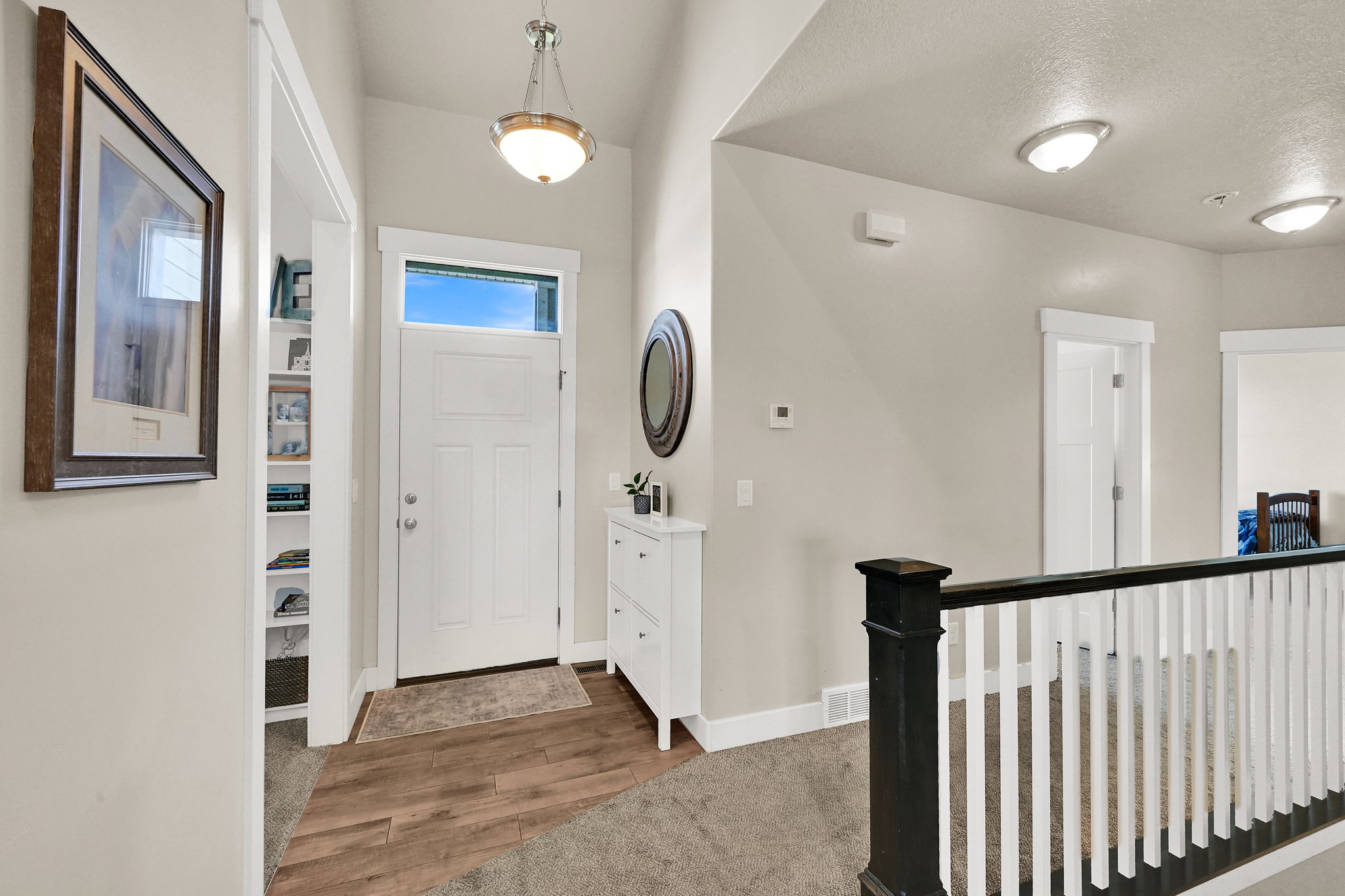 Entryway featuring a white paneled door with transom window, wood-finish flooring, recessed lighting, and a staircase with a white and dark-stained banister